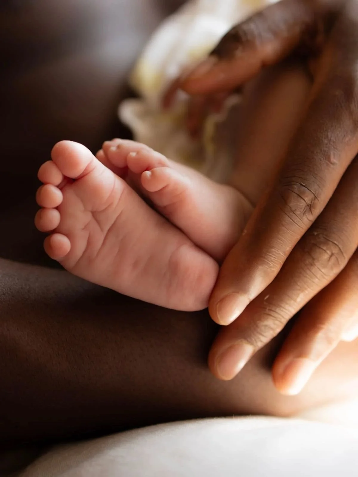 Une main d'adulte tenant doucement la main d'un bébé, symbolisant la protection et l'amour.