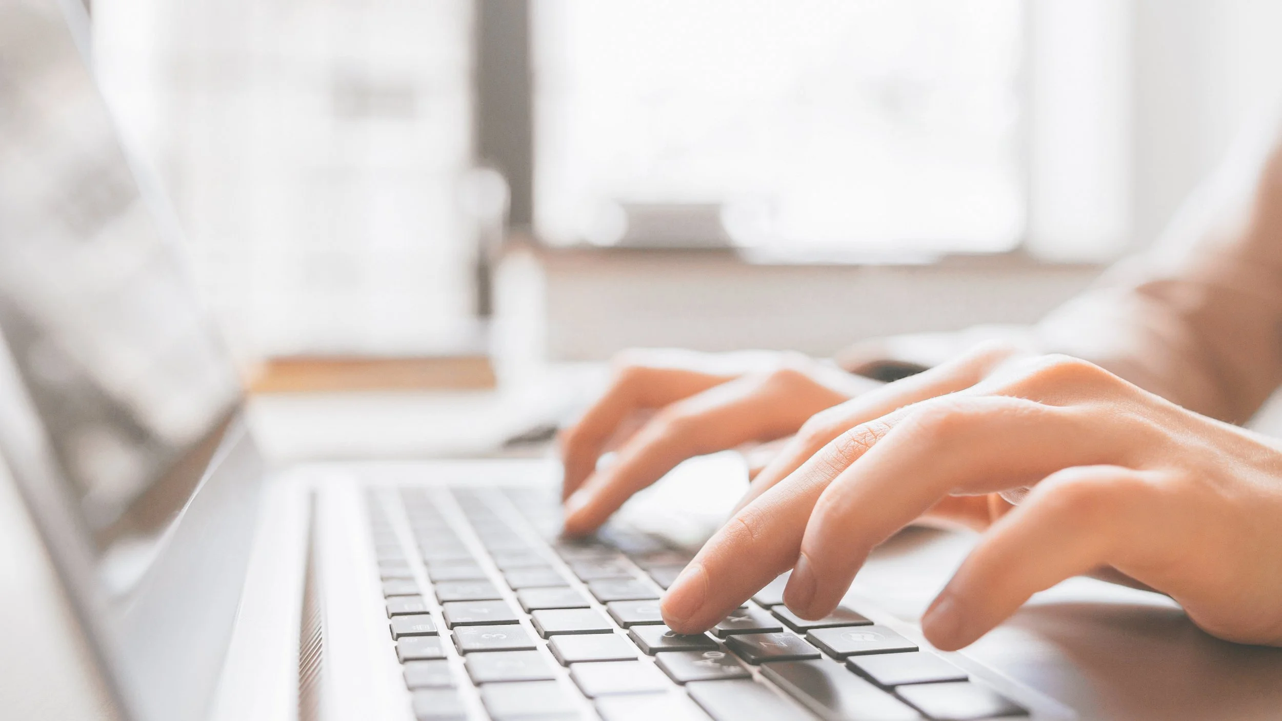 hands typing on a laptop keyboard