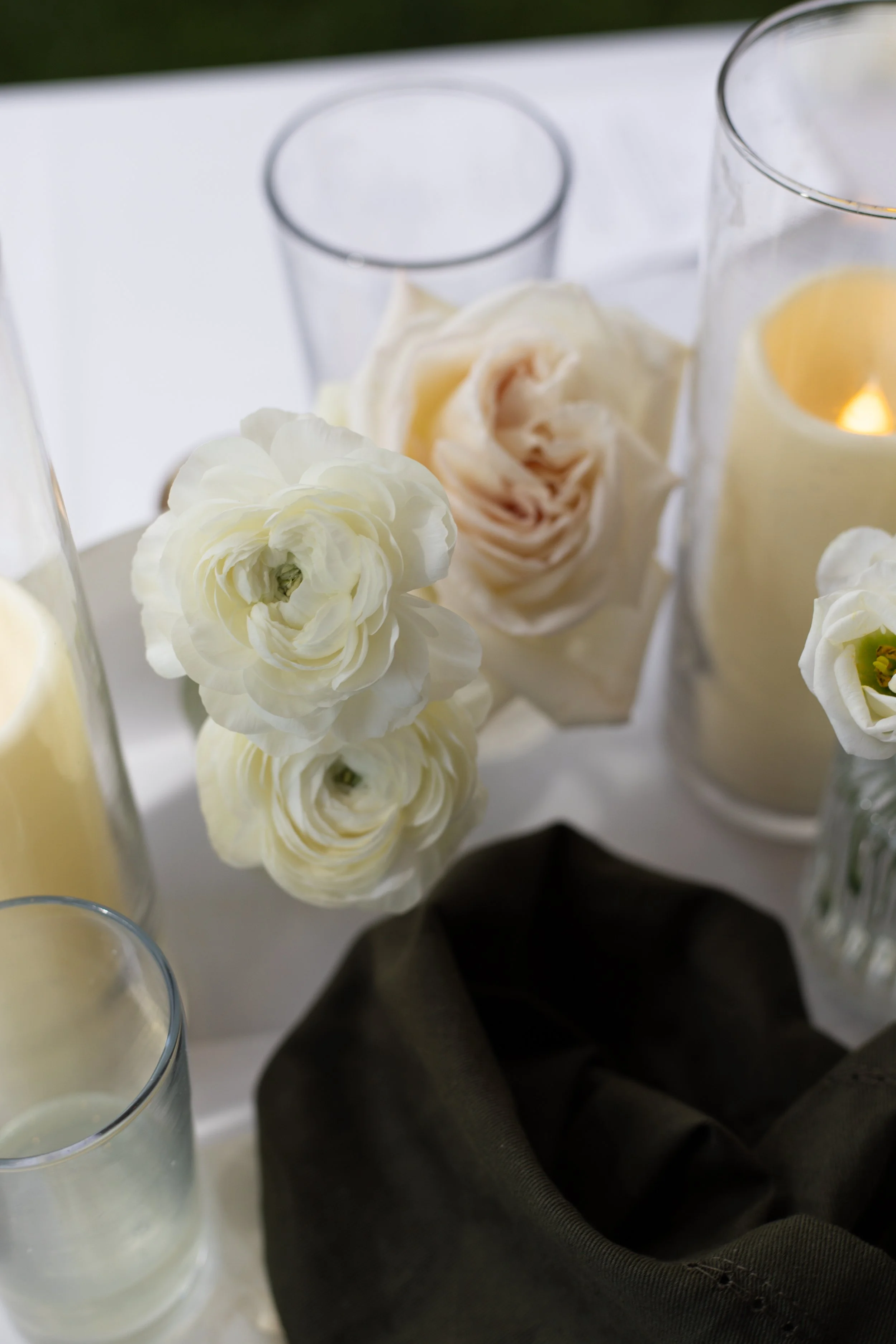 Close-up of white flowers, candles, and black fabric on a table.