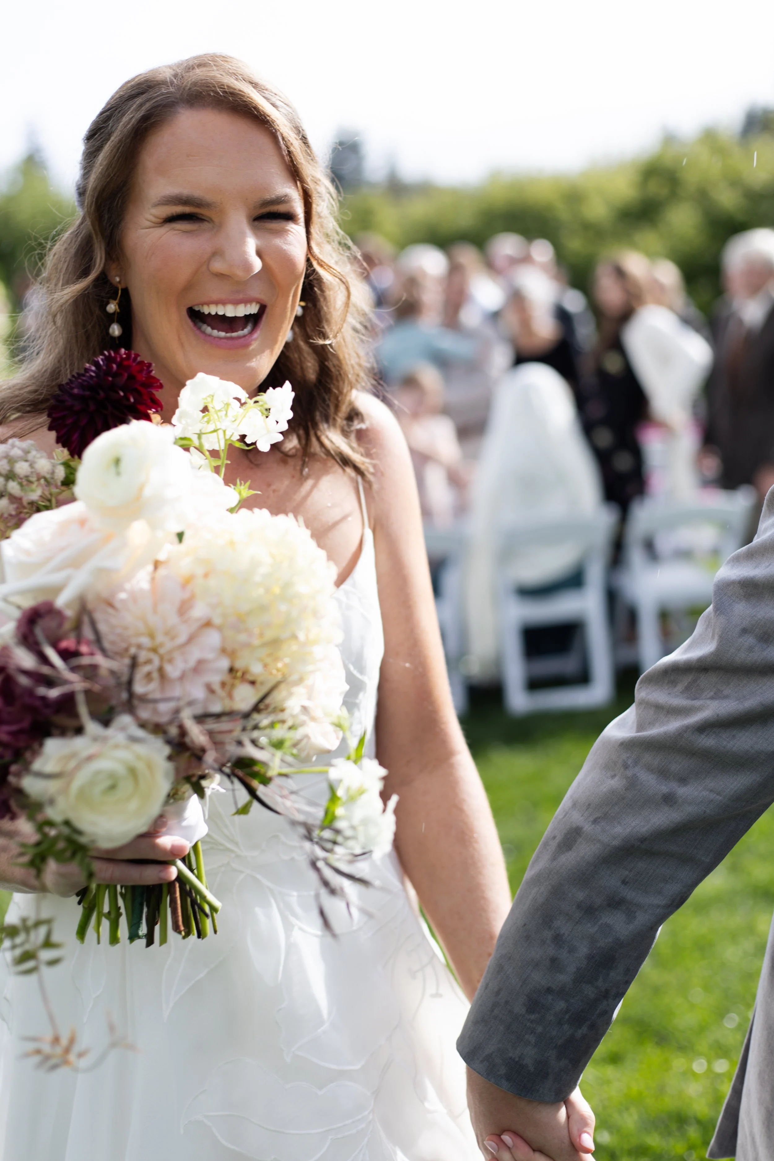 A bride right after her ceremony holding a bouquet of flowers, leaving the isle with her new husband in Hood River, Oregon