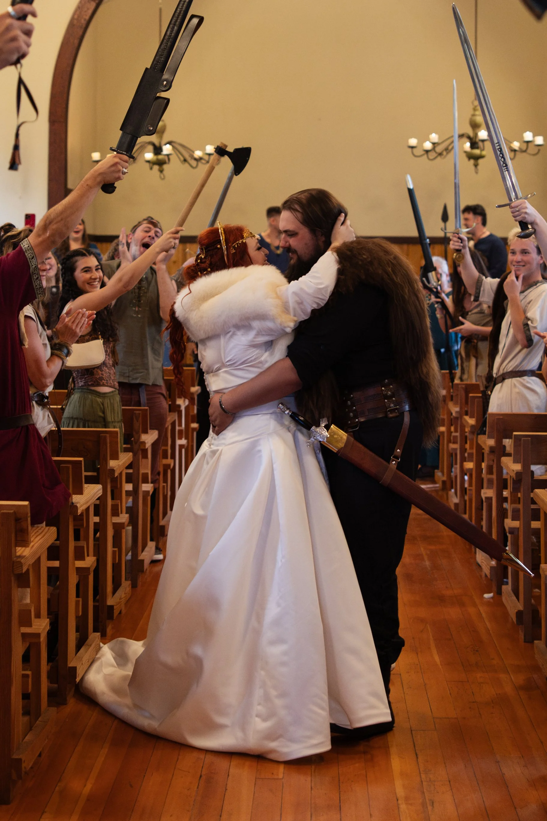 People in medieval costume with swords and axes in a church, embracing a castle wedding scene.