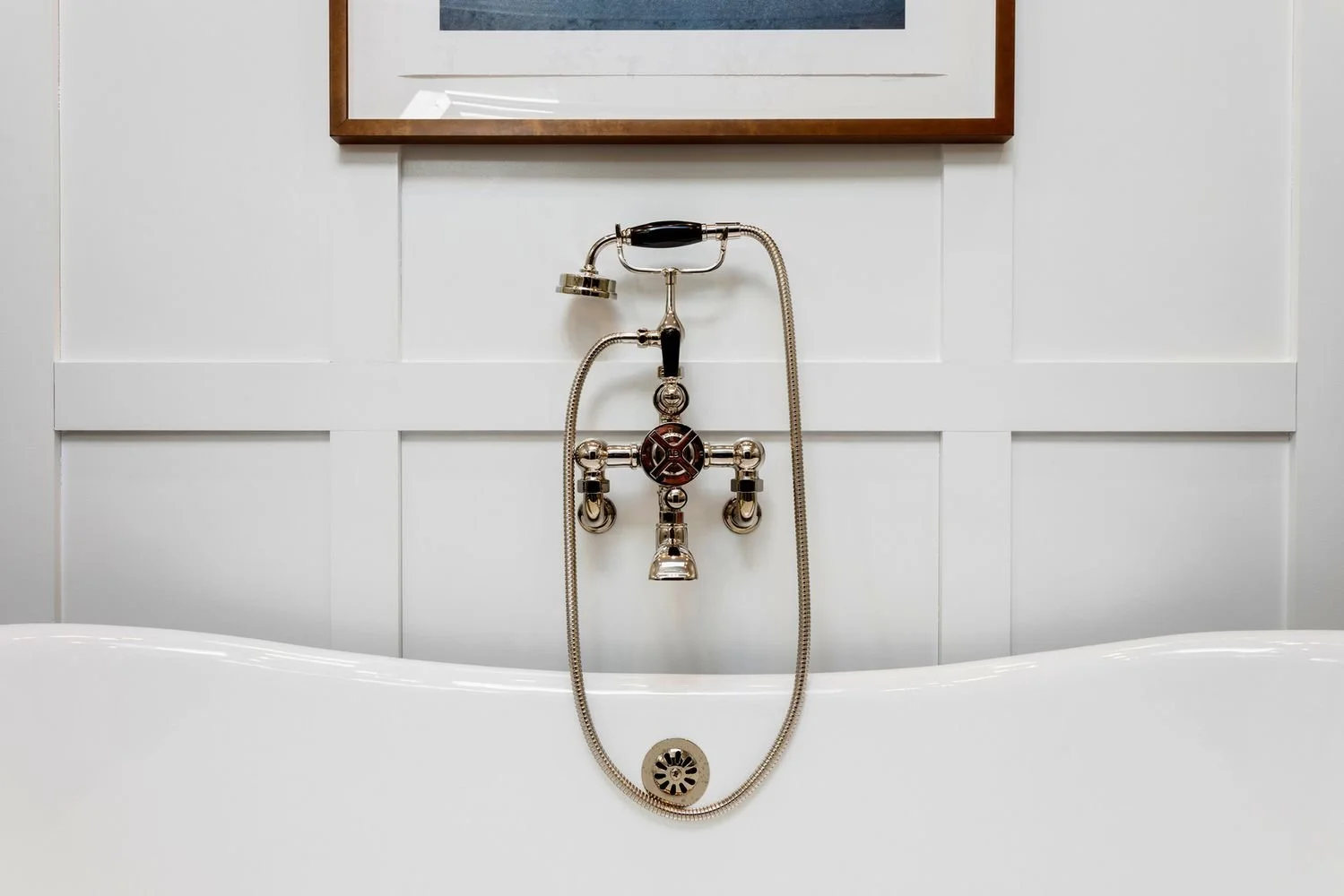 Wall-mounted tub filler with a hand shower above the soaking tub