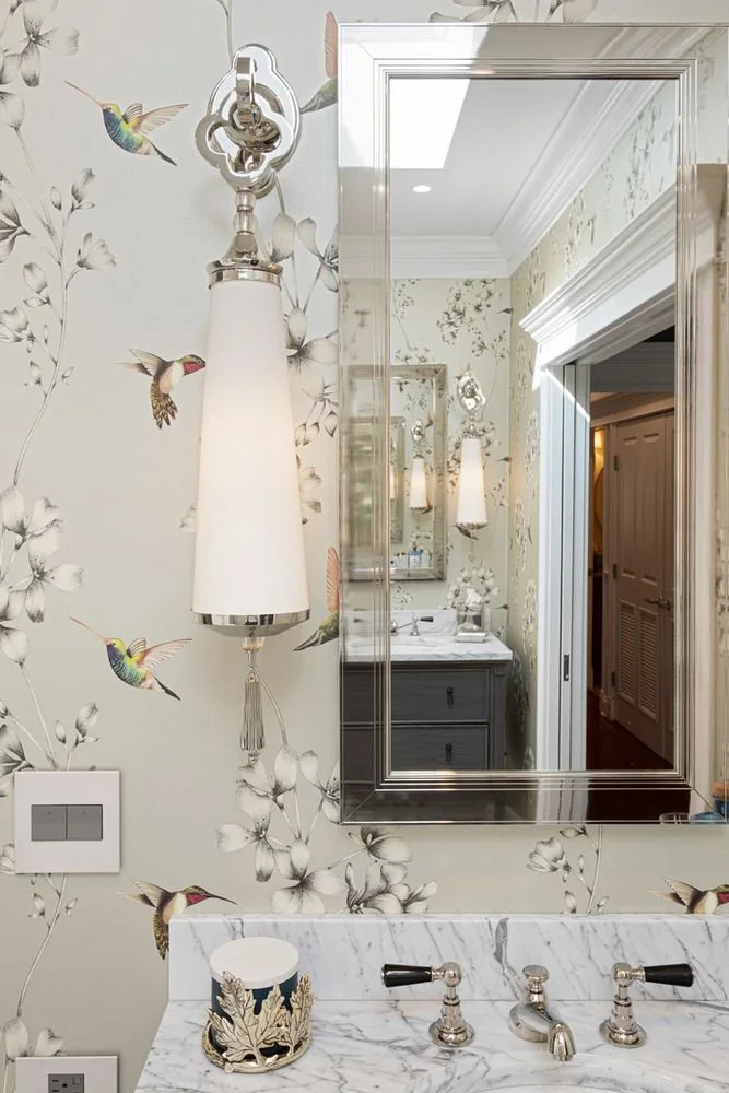 Botanical hummingbird wallpaper and a wall sconce in the primary bath
