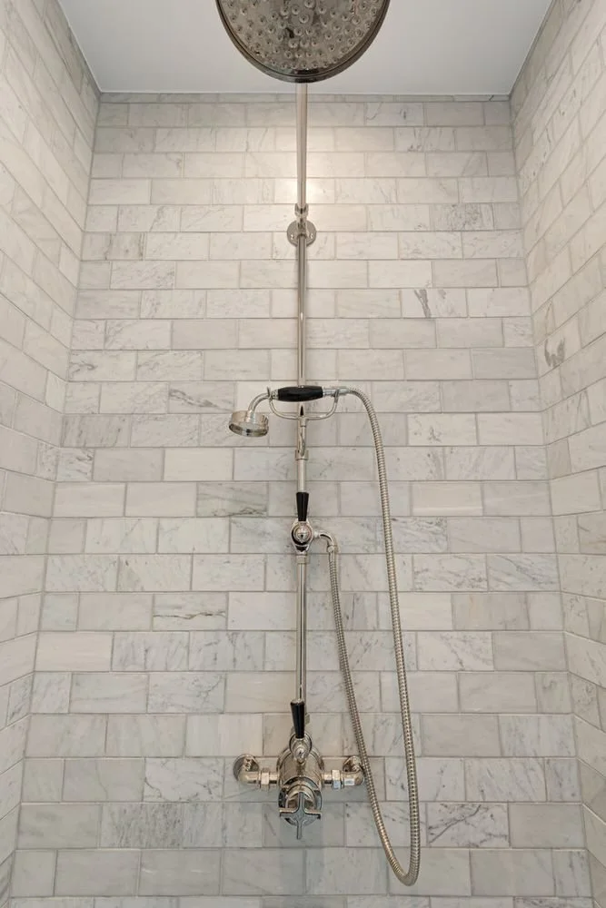 Marble-tiled shower with an exposed shower fixture