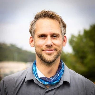 Jeff Hester smiling outdoors with greenery in the background