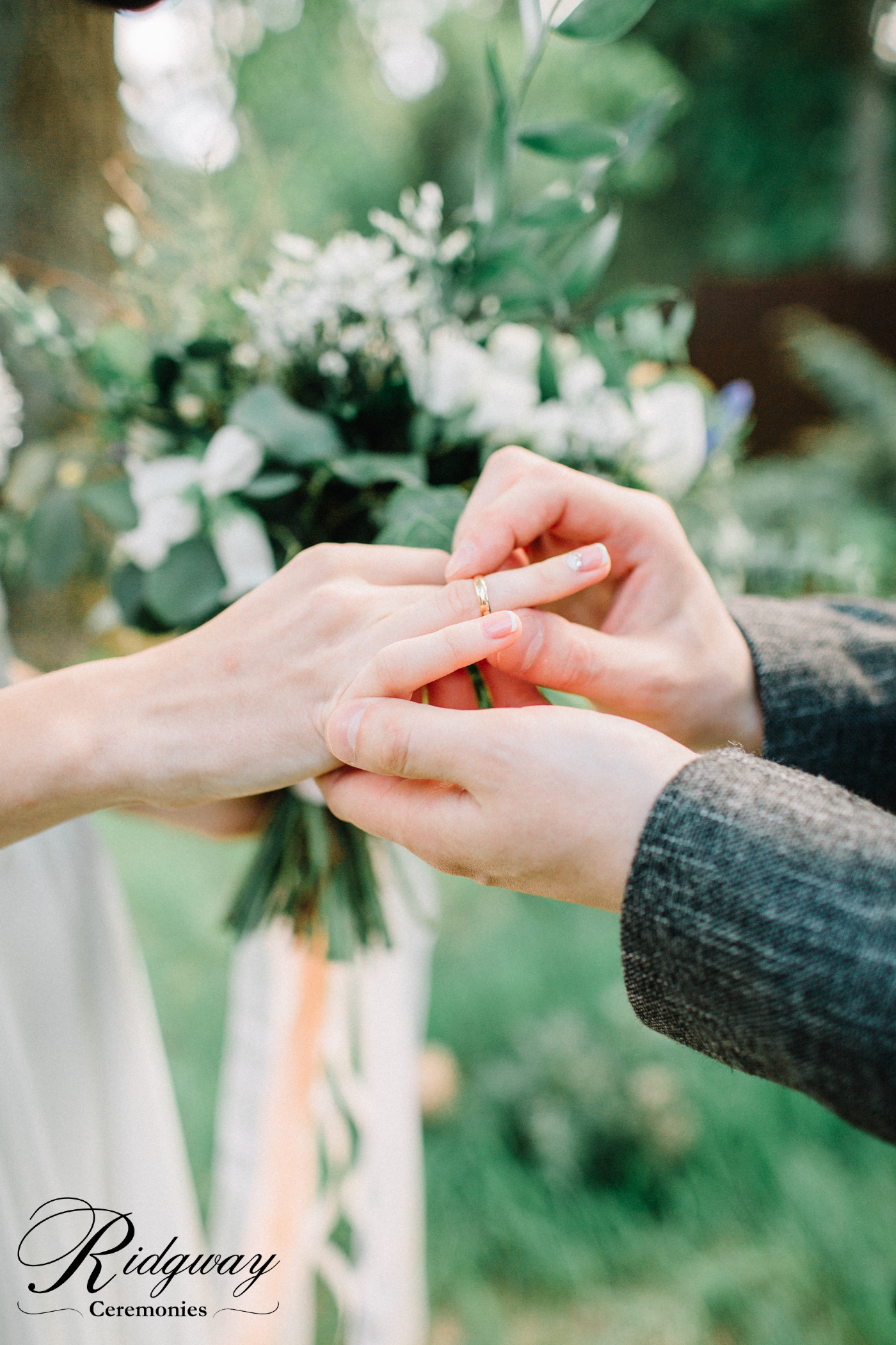 Close-up of a person wearing a wedding ring holding hands with another person in an outdoor setting.