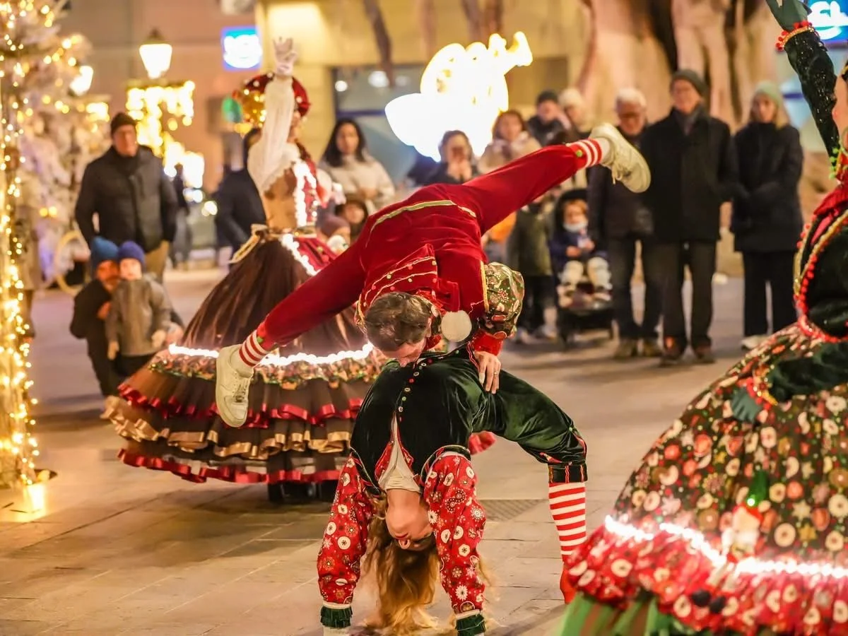 Deux personnes déguisées en costumes de Noël font une acrobatie de danse dans une fête de Noël en plein air, avec des spectateurs en arrière-plan. Dans les alpes maritimes 06 à Cannes.