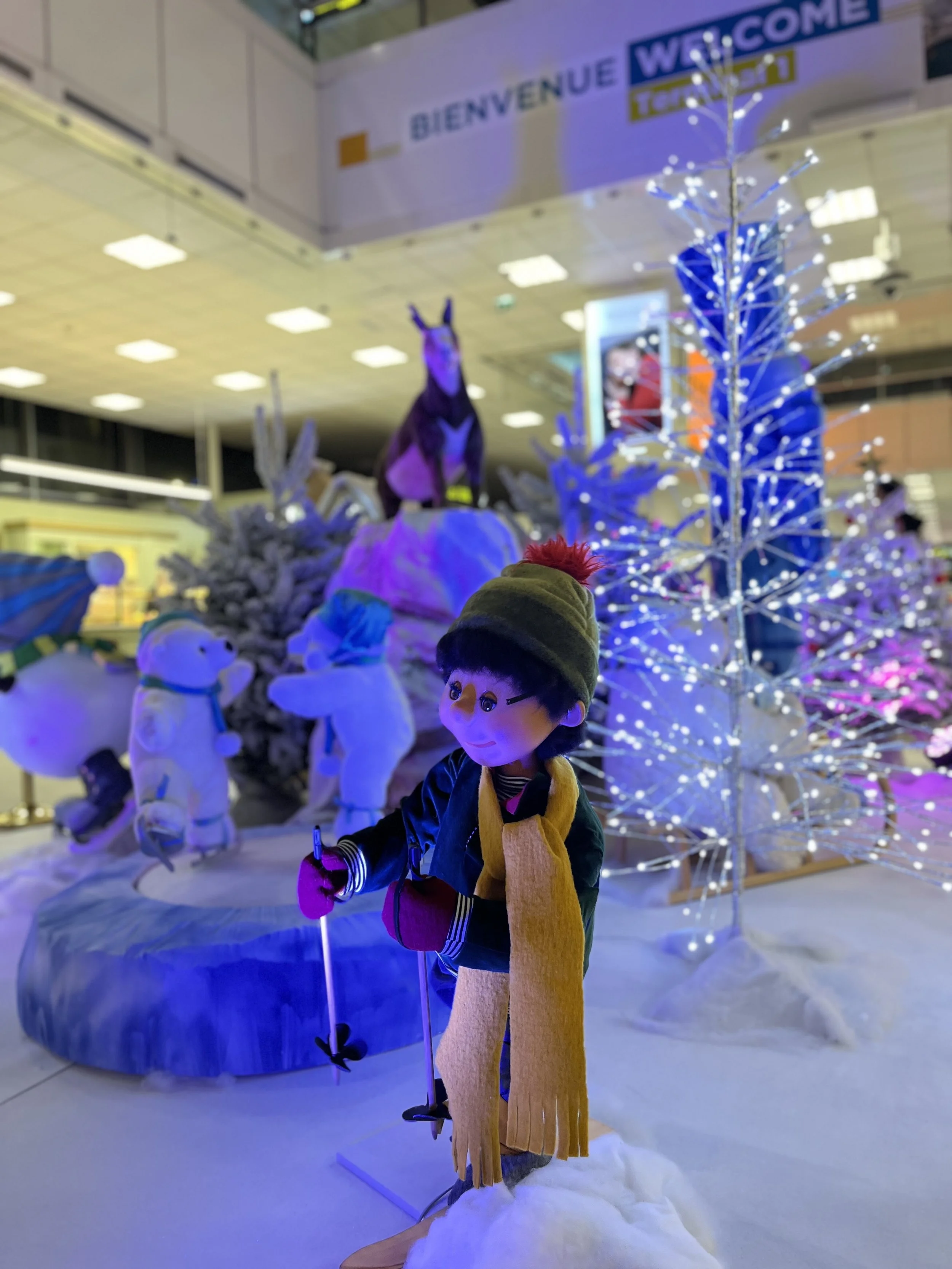 Décoration de Noël dans un aéroport, avec des décorations festives, des automates animatroniques en peluche et des illuminations de Noël.