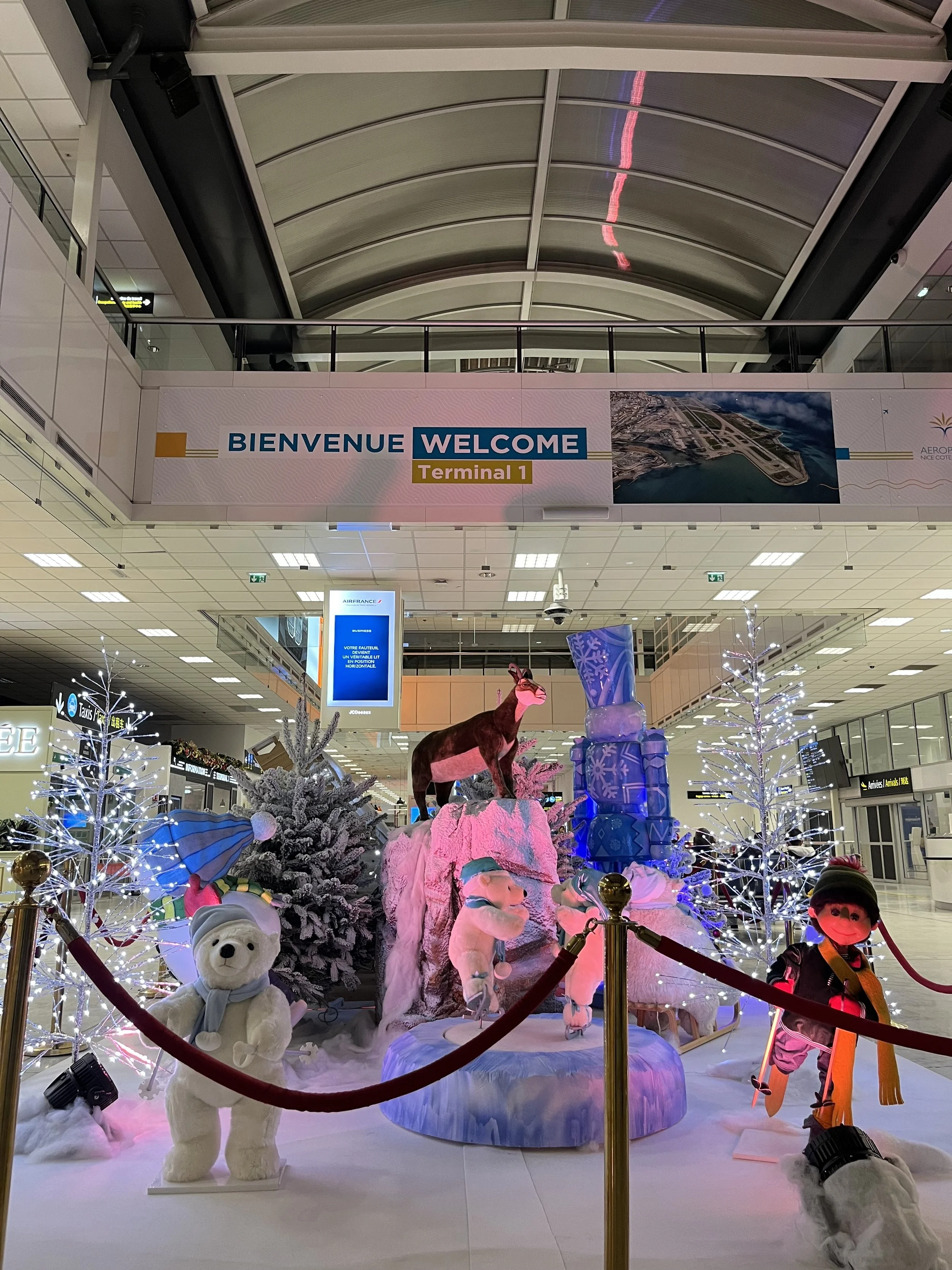 Décoration de Noël dans un aéroport, avec des décorations festives, des automates animatroniques en peluche et des illuminations de Noël.