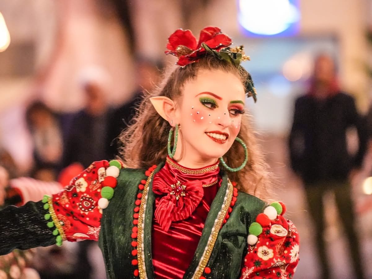 Femme déguisée en elfie ou personne dans un costume festif rouge et vert, avec maquillage coloré, boucles d'oreilles vertes, un bandeau floral rouge sur la tête.Dans les alpes maritimes .