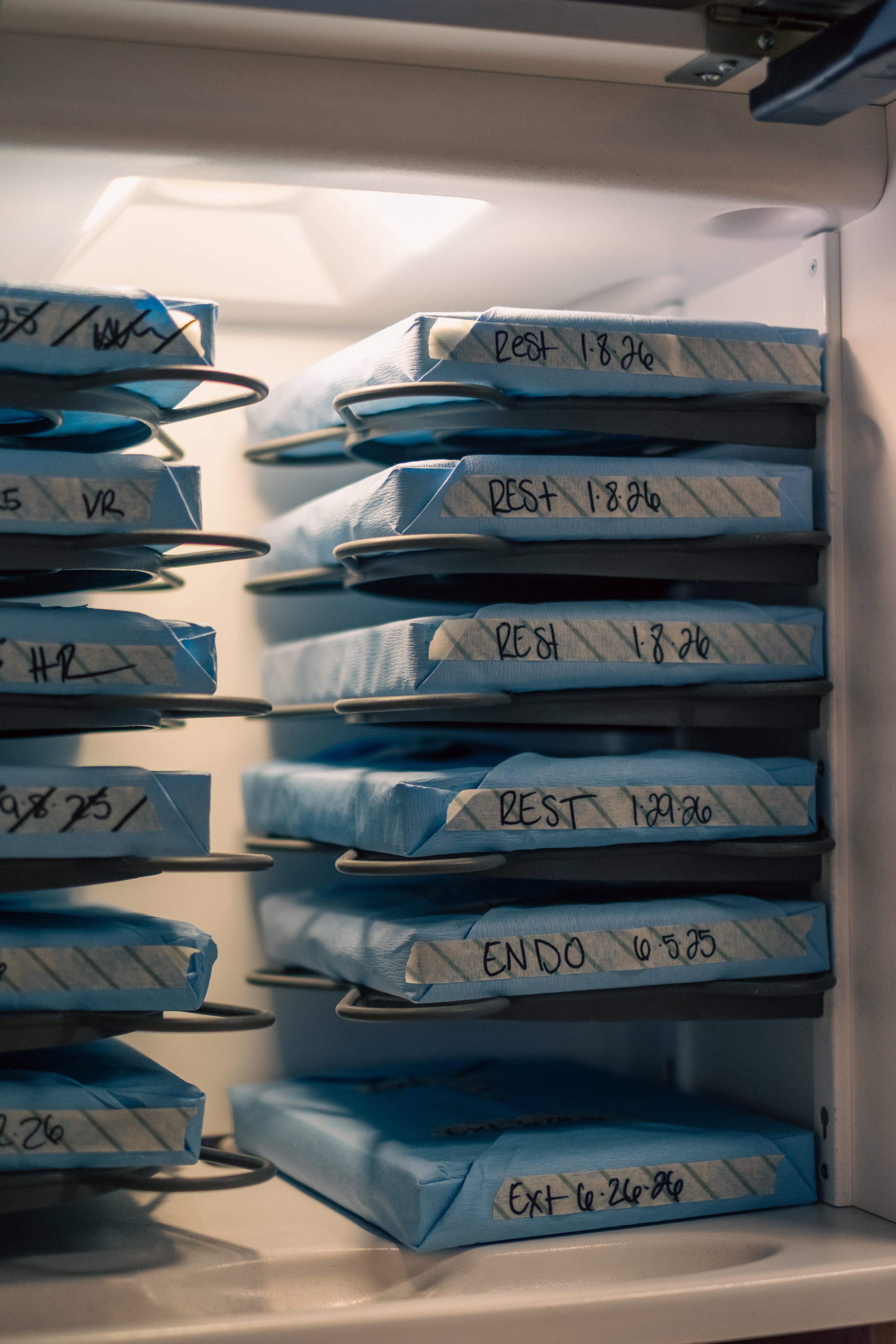 The inside of a refrigerator with multiple shelves holding wrapped packages labeled with dates and times.