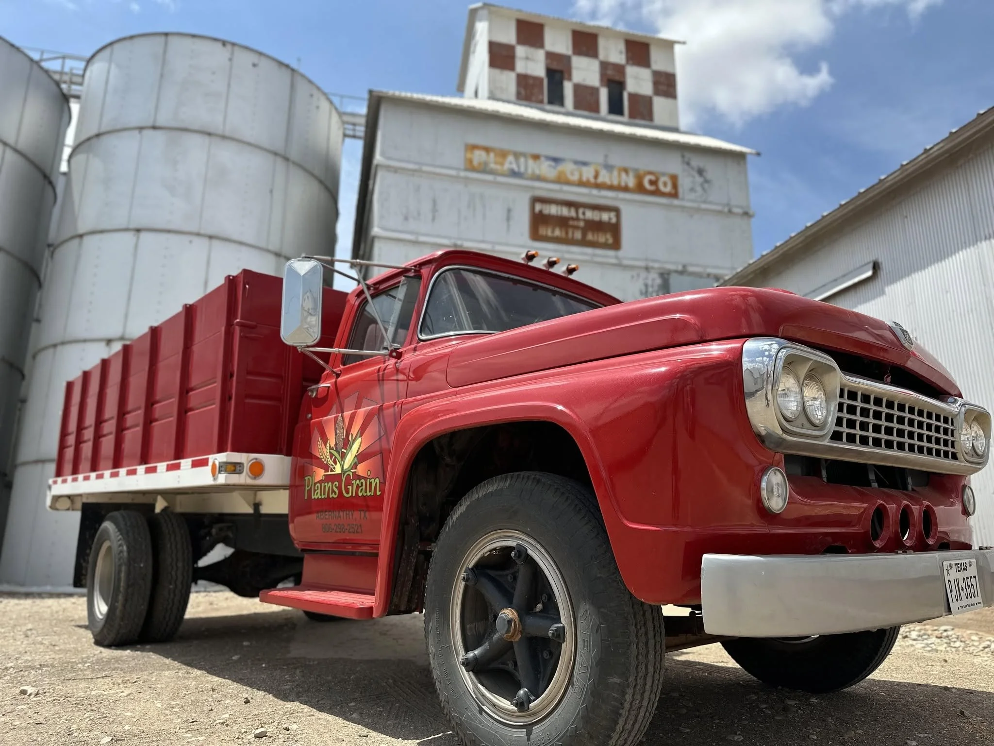 Red pickup truck in foreground with grain elevator in background
