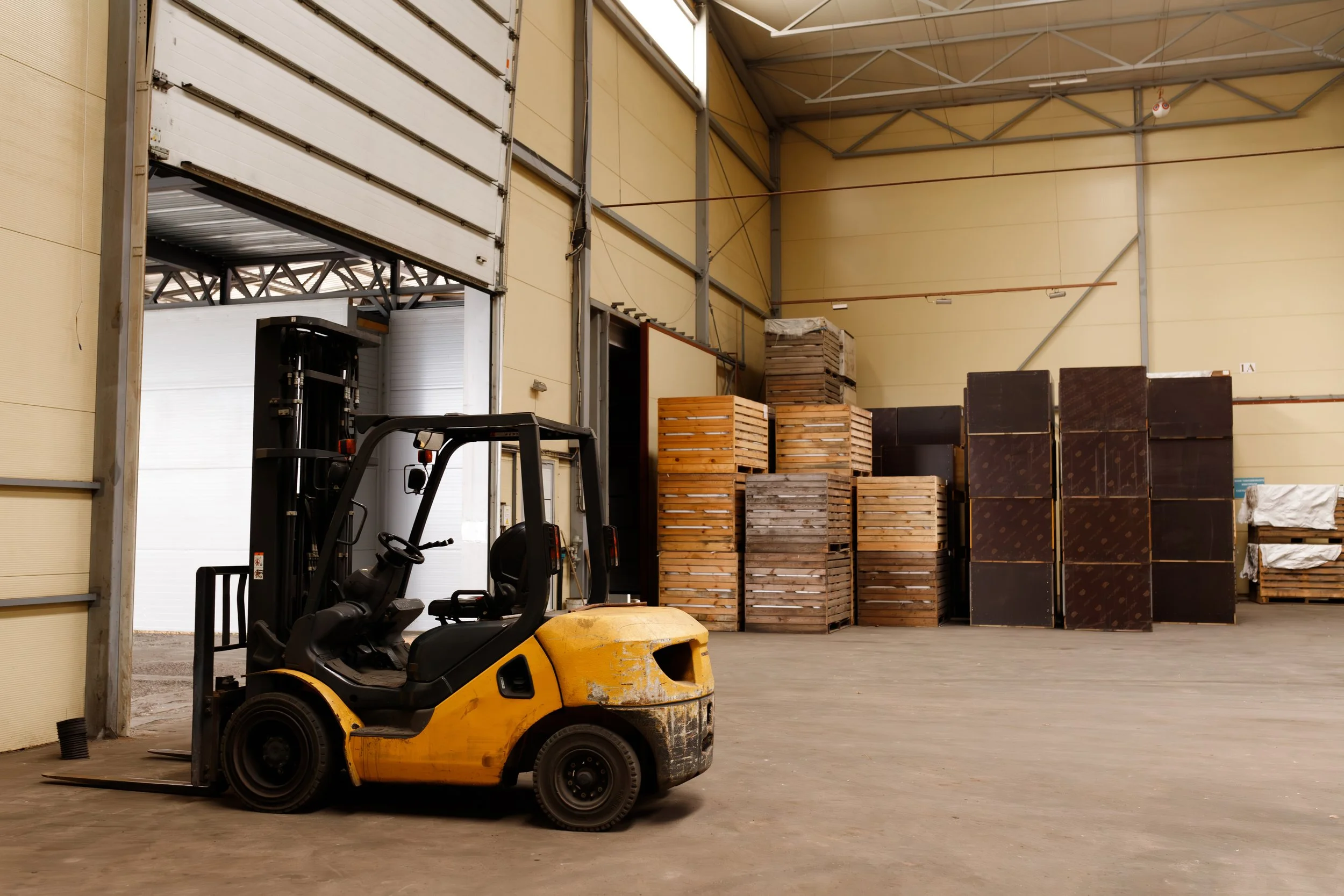Warehouse space for lease with stacked pallets and forklift in foreground