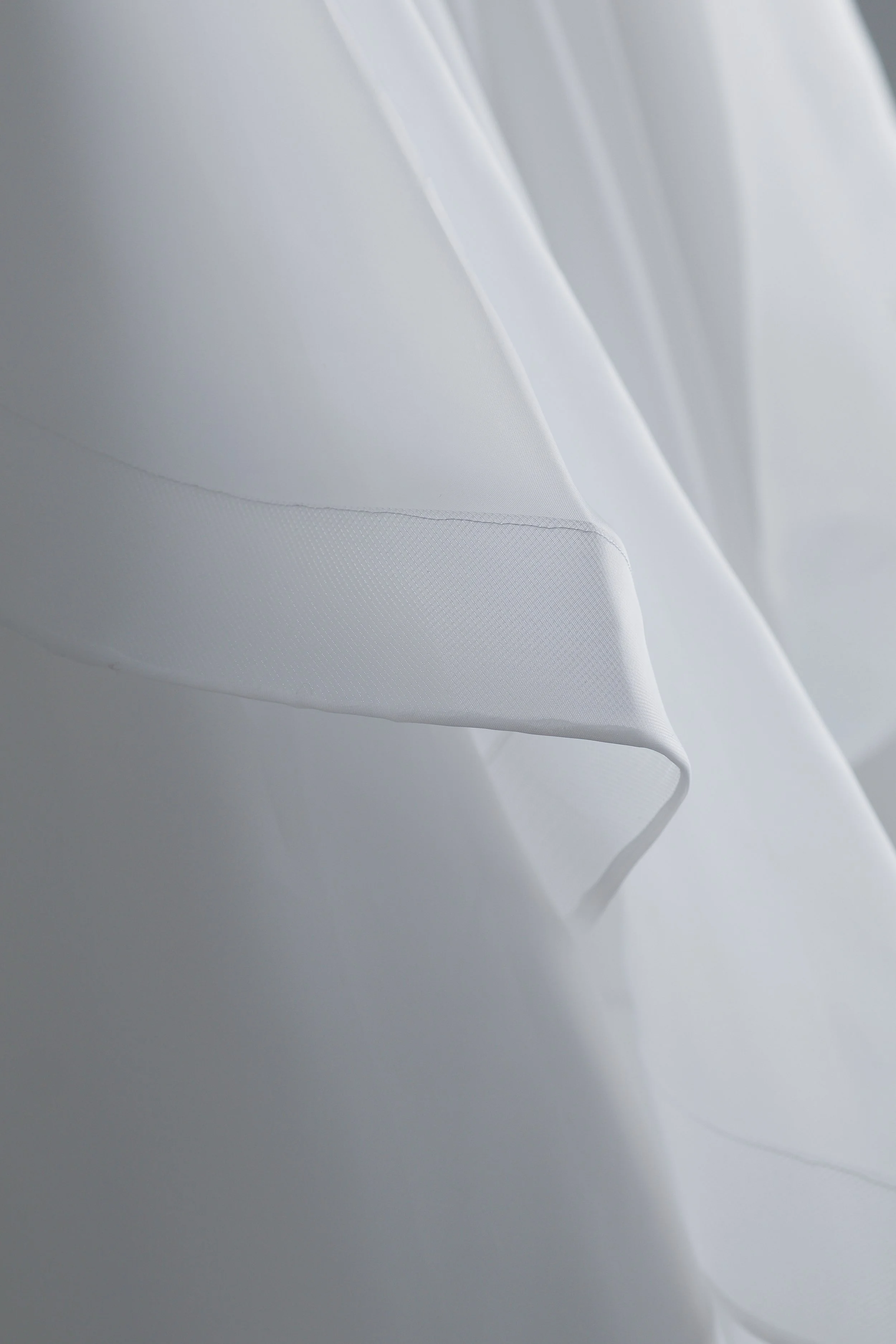 Close-up of white fabric with soft folds and a subtle textured pattern.