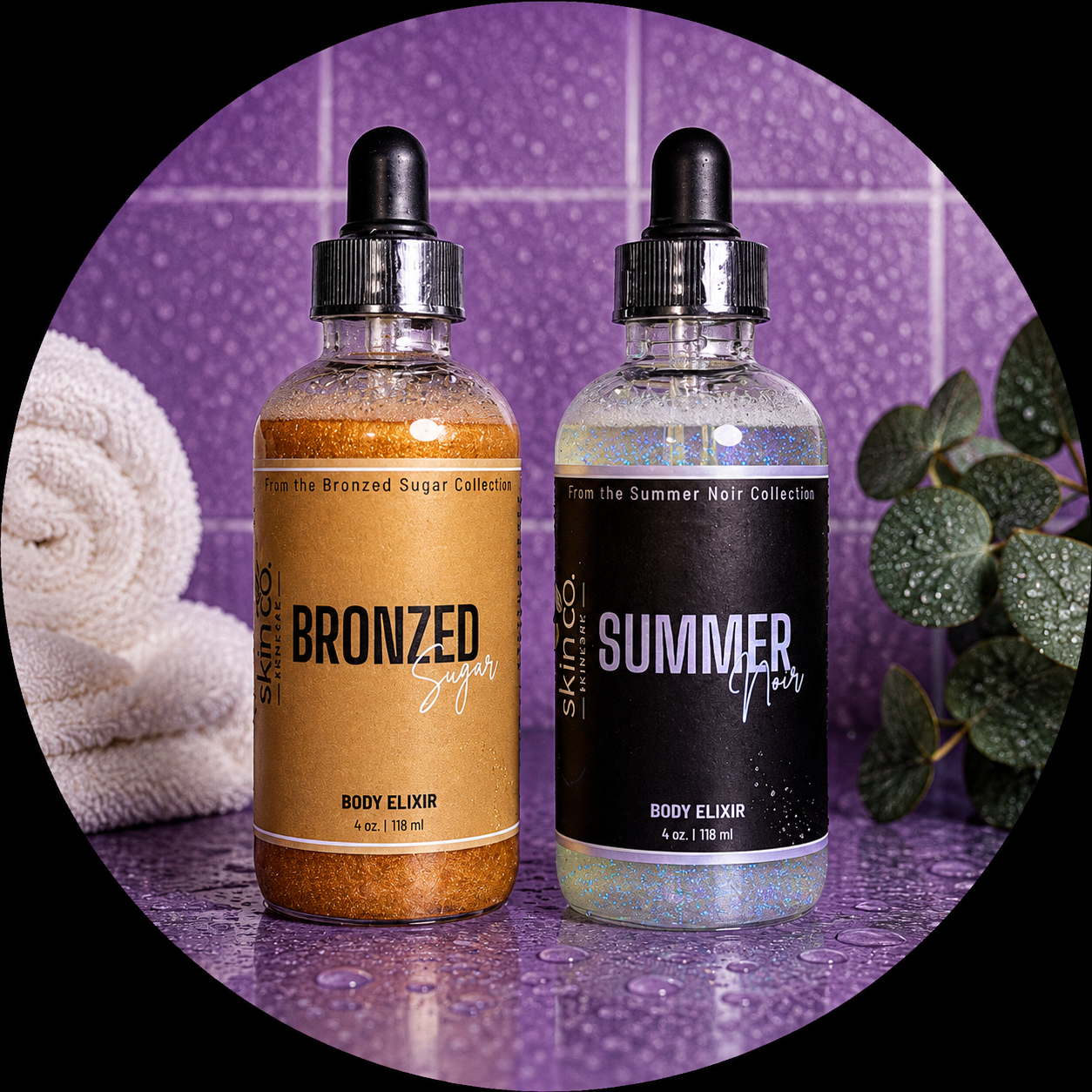 Two body elixir bottles, one labeled 'Bronzed Sugar' from the Bronzed Sugar Collection and the other labeled 'Summer Noir' from the Summer Noir Collection, are placed on a wet purple countertop with a purple tiled wall in the background. There is a rolled towel on the left and a leafy plant on the right.