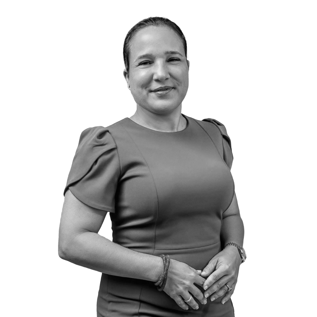 Black and white photo of a woman wearing a dress with puffed sleeves, smiling slightly, with her hands clasped in front of her, standing against a gradient background.