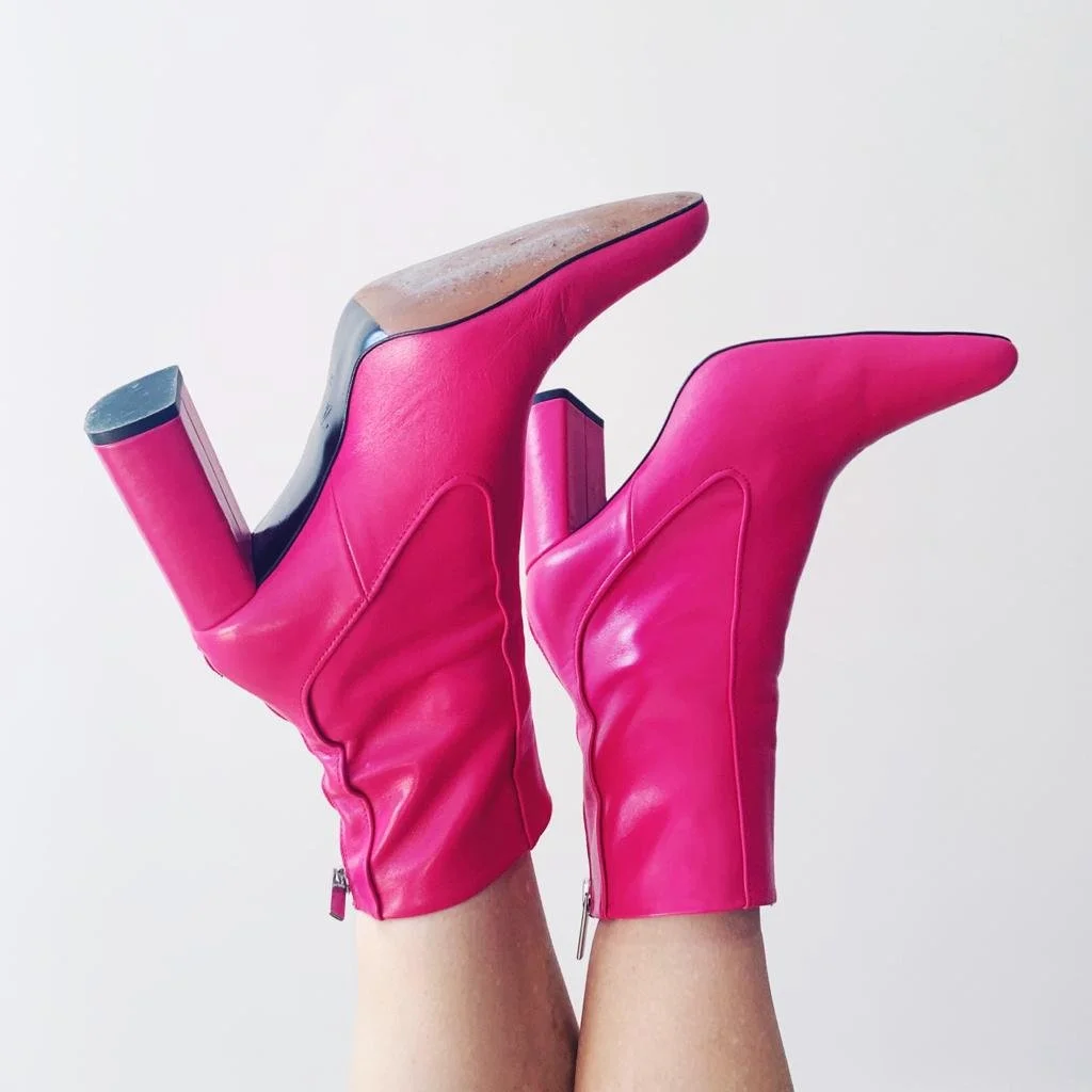 Pair of bright pink high-heeled ankle boots with pointed toes, heels facing upward, against a plain white background.