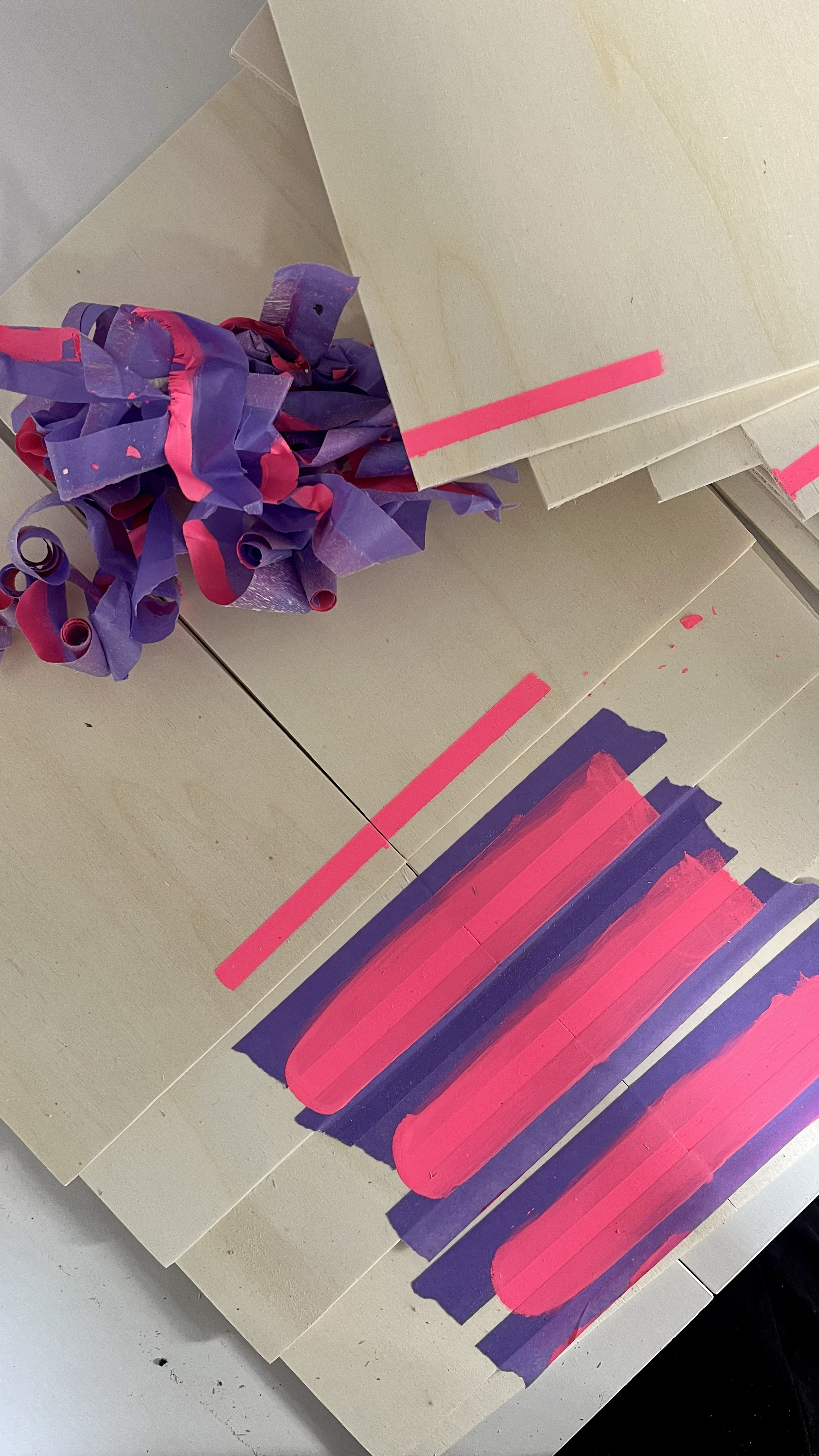 Colorful abstract art featuring pink and purple paint strokes on beige cardboard with crumpled purple and pink paper pieces.