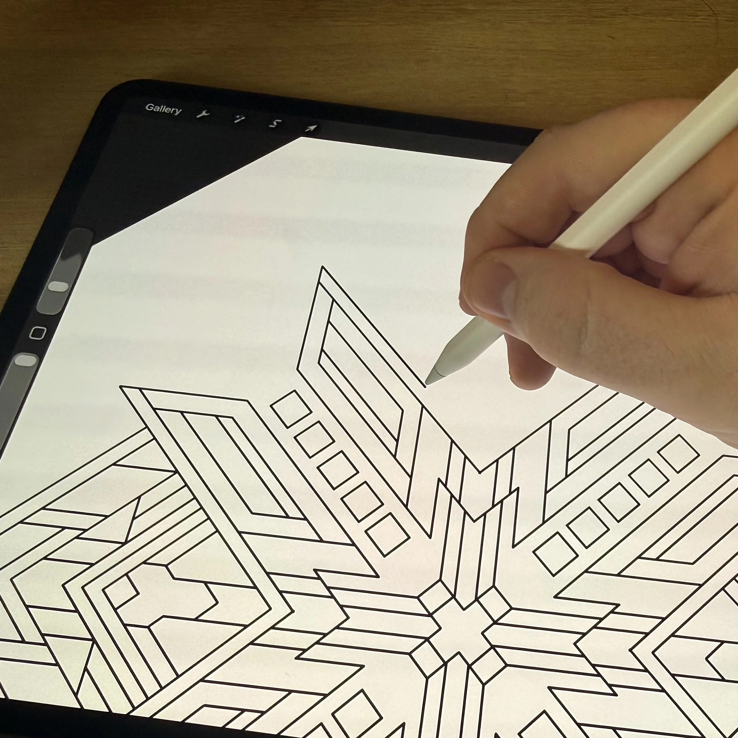Close-up of a tablet screen with a coloring book page of geometric patterns, held by a person's hand.