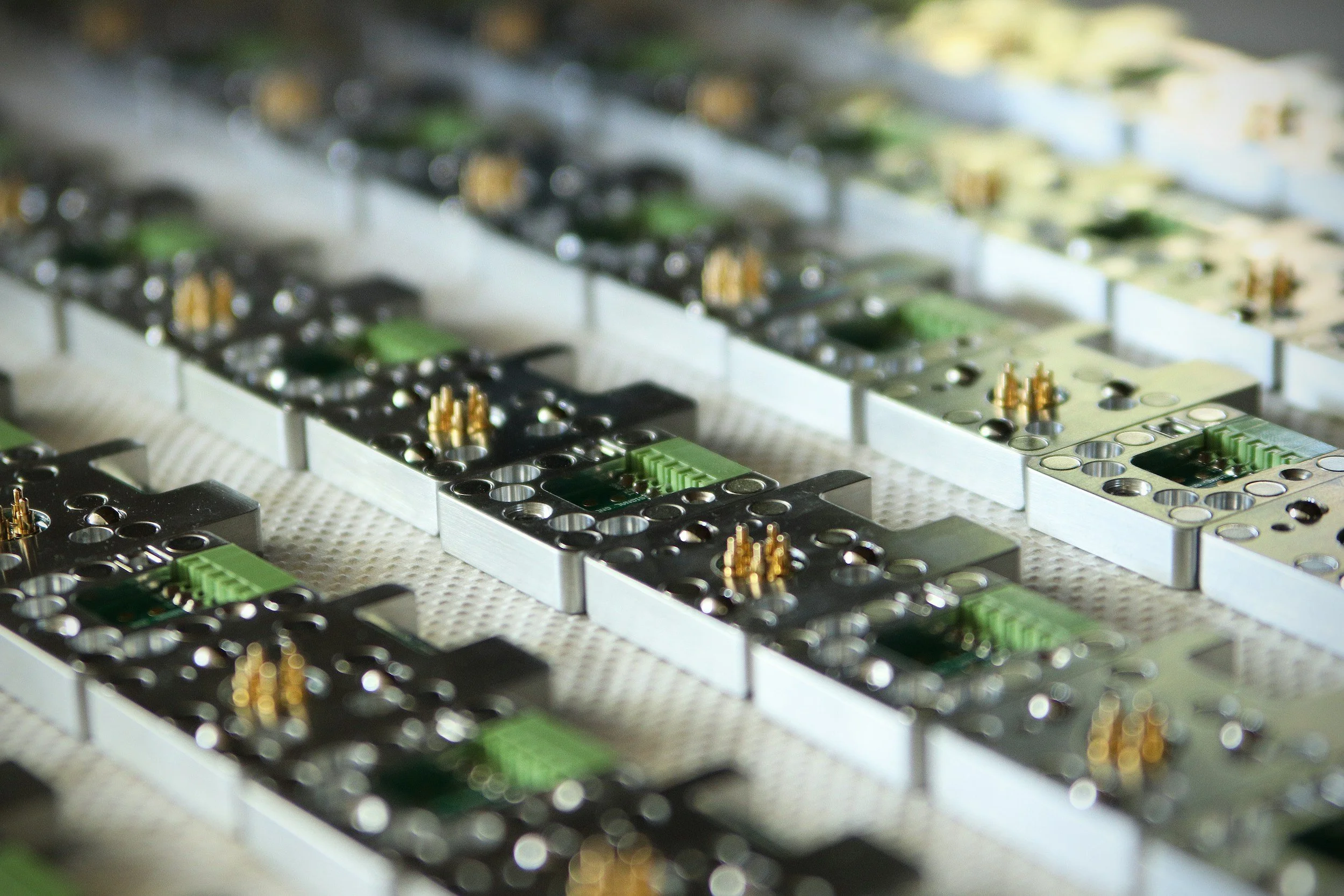 Close-up of a circuit board with electronic components, including green and gold elements, mounted on a metal base.