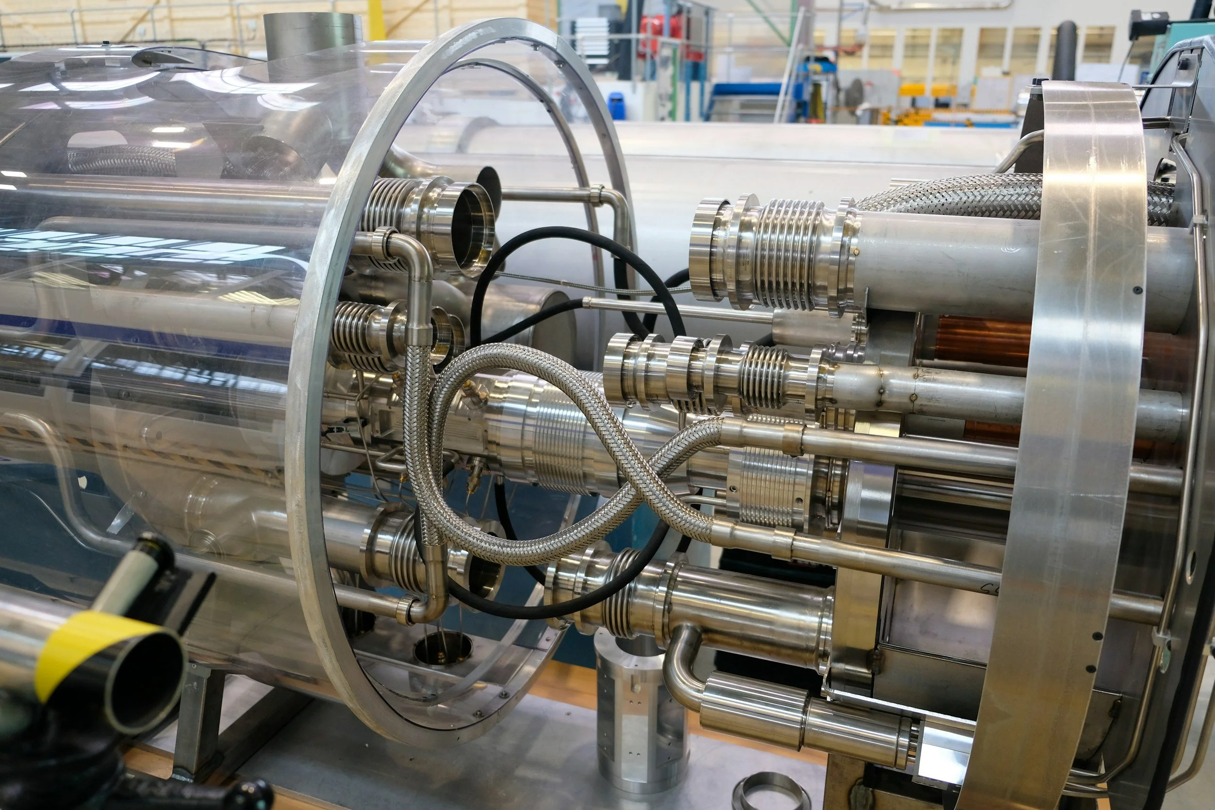 Close-up of a complex stainless steel machinery with pipes, tubes, and components in an industrial setting.