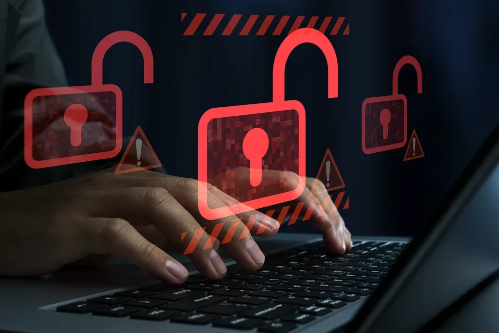 Hands typing on a laptop keyboard with digital padlock and warning icons overlay, symbolizing cybersecurity or data protection.