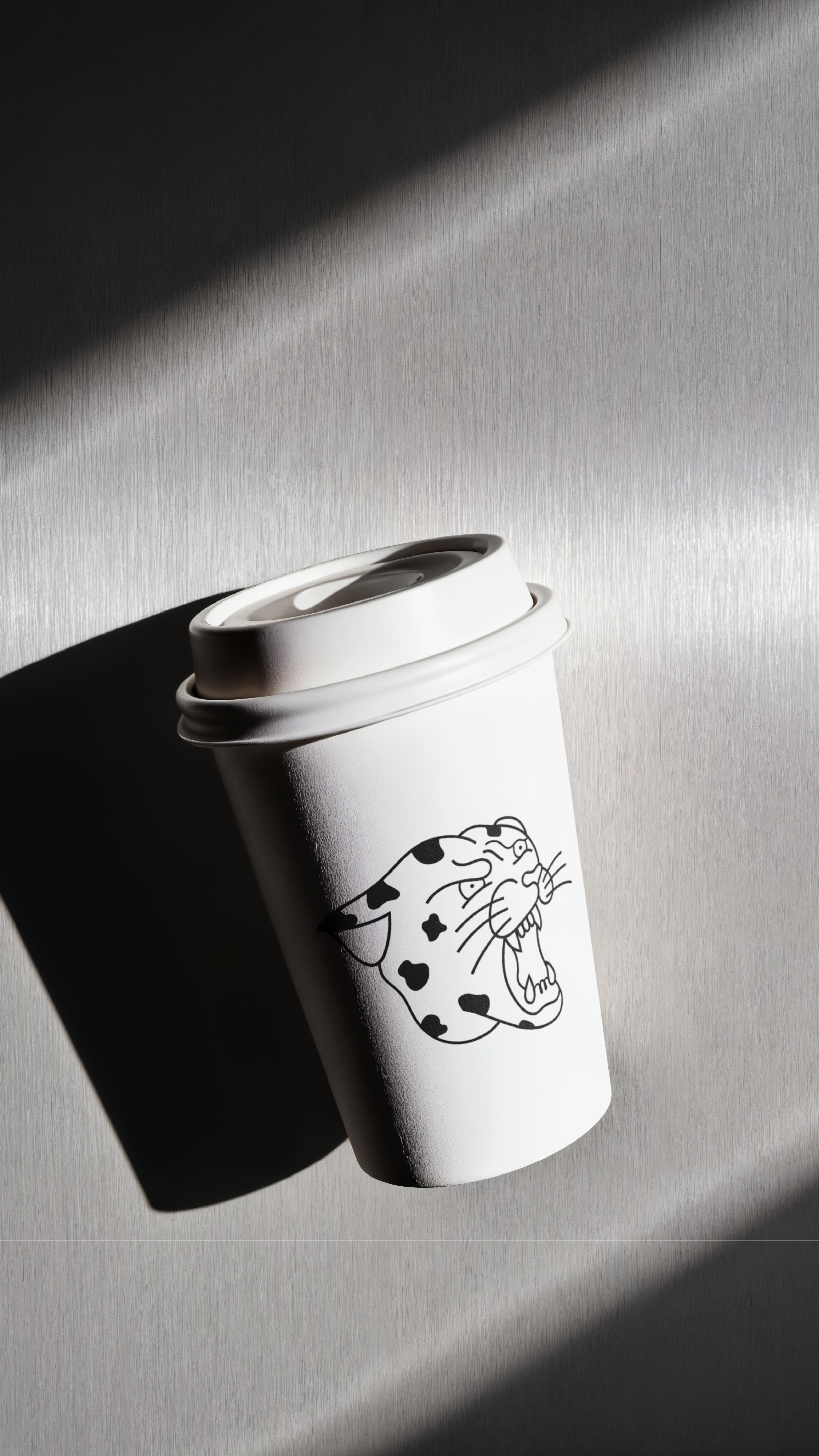 A white disposable coffee cup with The Daily Grind logo on it, placed on a light-colored textured surface near a shadow.