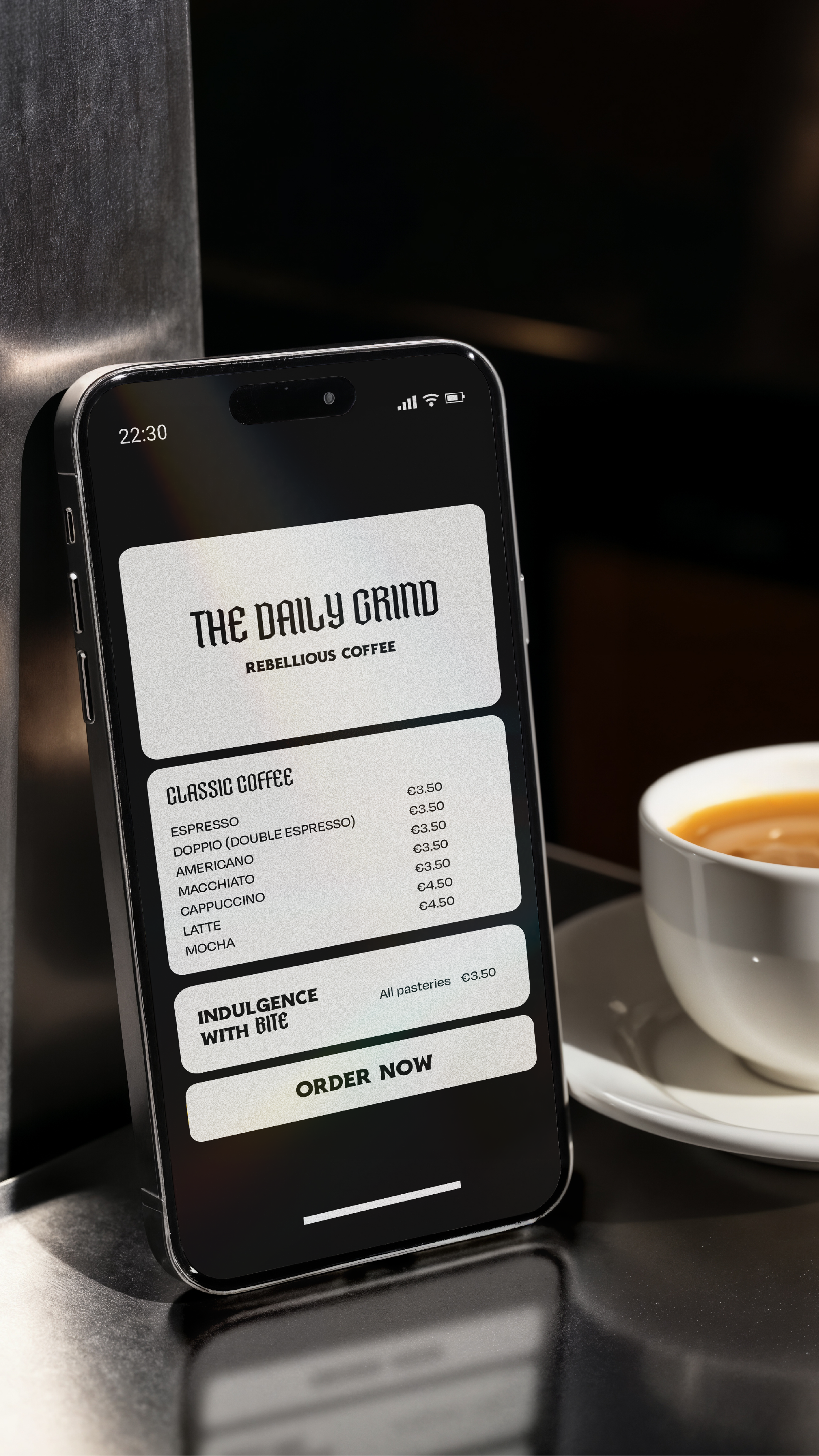 Smartphone displaying The Daily Grind coffee menu with options like espresso, double espresso, americano, cappuccino, latte, mocha, and prices in euros, placed next to a cup of coffee on a saucer. The Daily Grind logo is at the top of the menu.