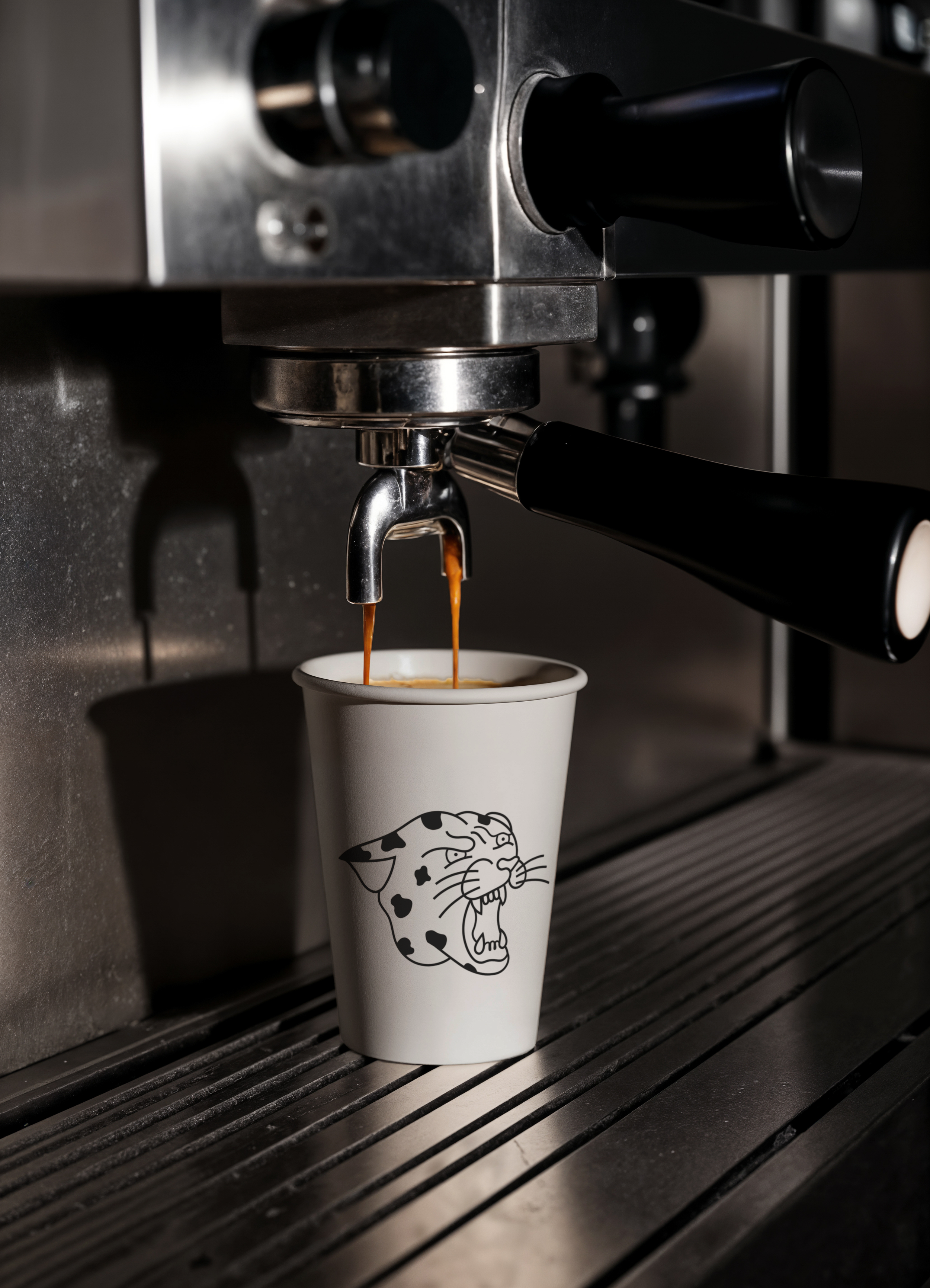 Espresso being brewed into a cup with The Daily Grind brand mark on it, under a coffee machine spout.