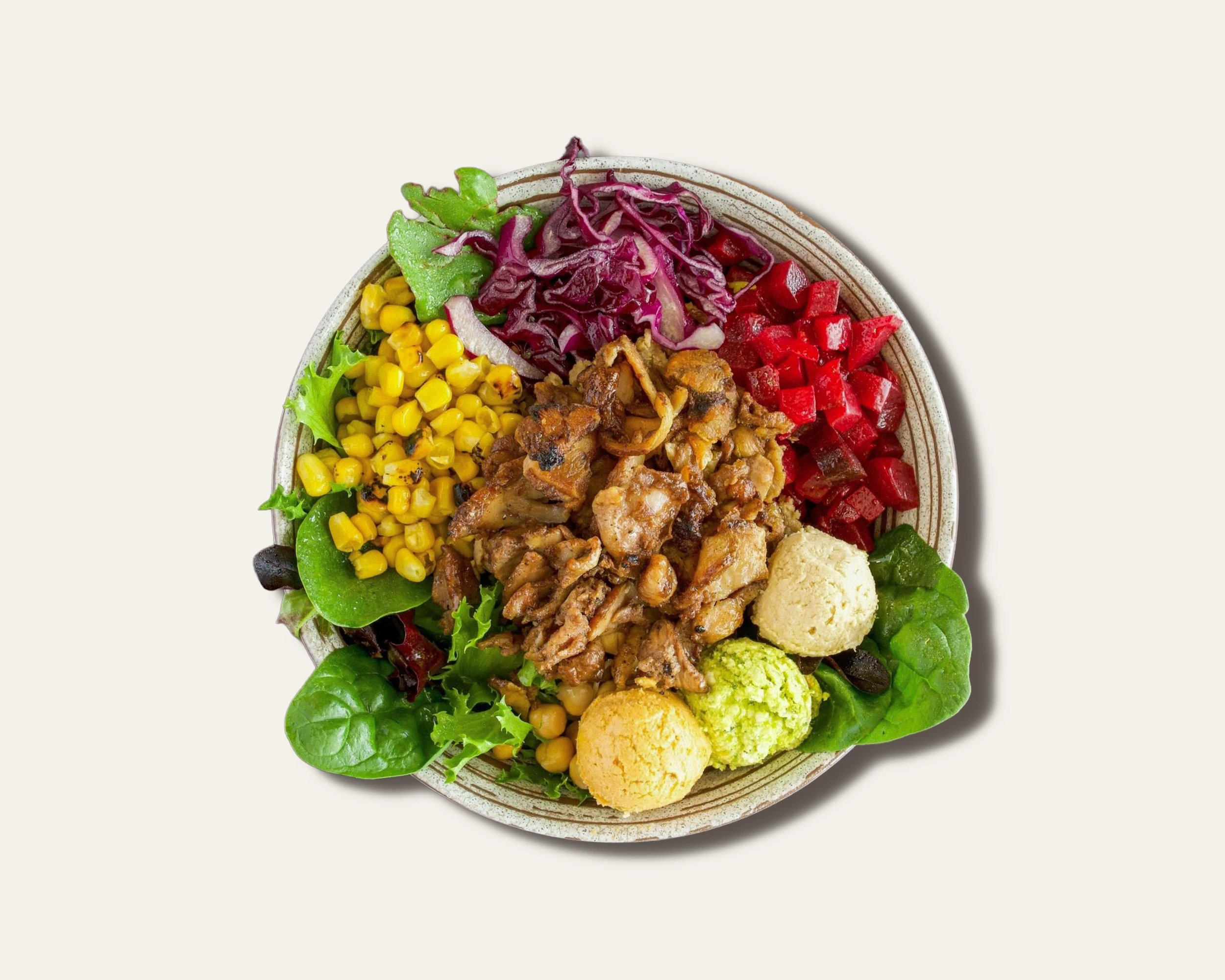 A bowl of salad containing lettuce, corn, shredded red cabbage, diced red bell peppers, grilled chicken pieces, cauliflower, and sliced olives.