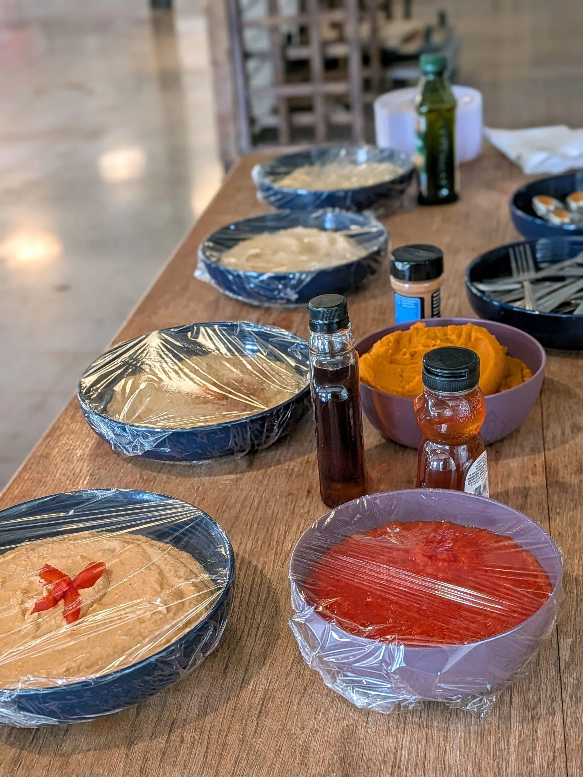 A table with several covered dishes, bowls of mashed sweet potatoes, and various sauces and condiments, in a casual dining or buffet setting.