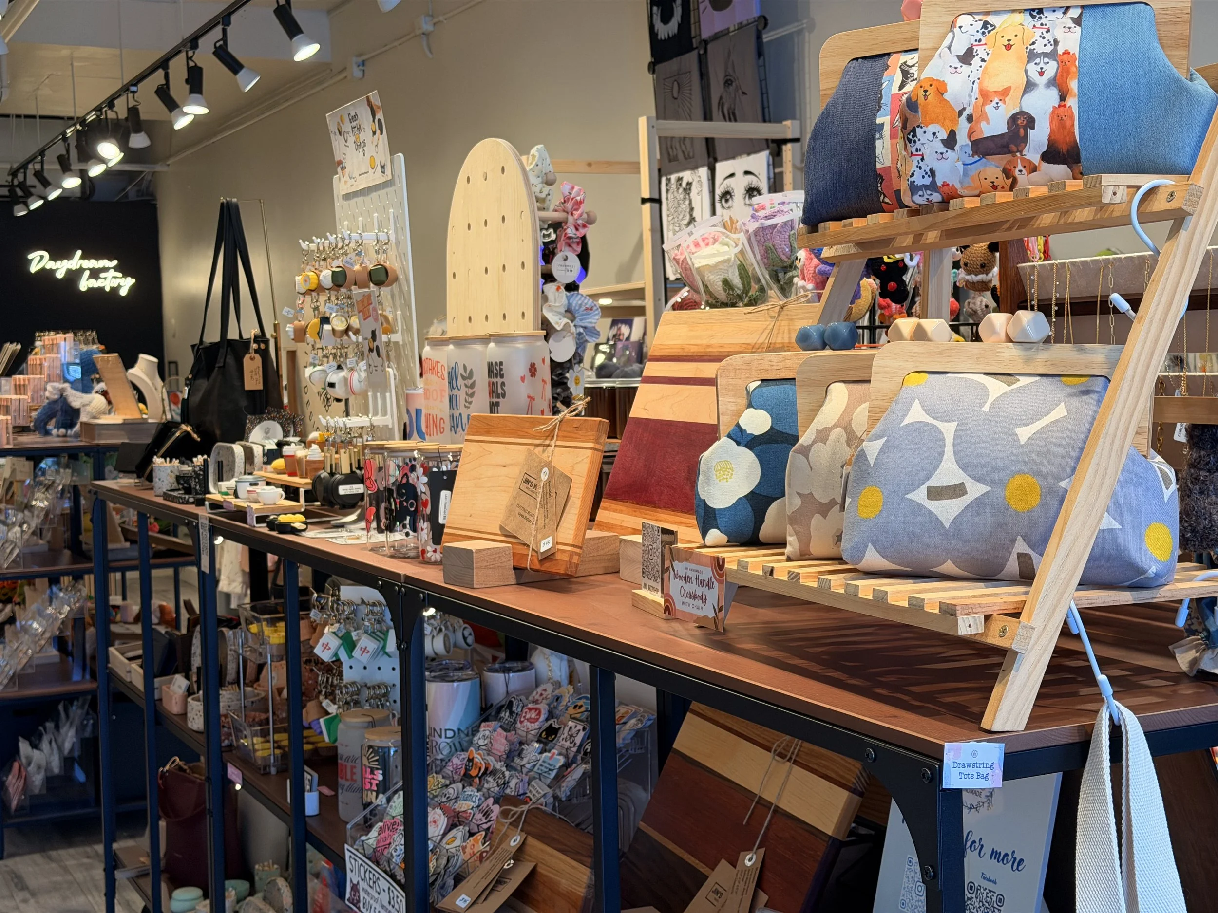 Display of various home decor and gift items in a retail store, including pillows with dog print, craft materials, and wooden displays.