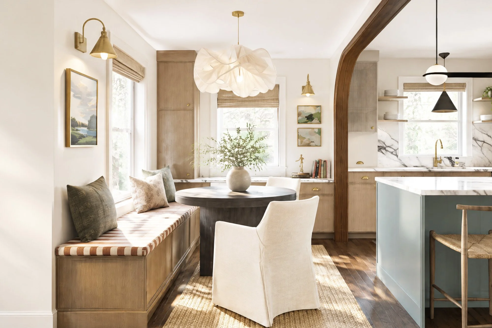 Warm, layered dining and kitchen area featuring built-in bench seating, a dark wood dining table, upholstered dining chairs, custom office cabinetry with access to the kitchen through a wood-trimmed archway