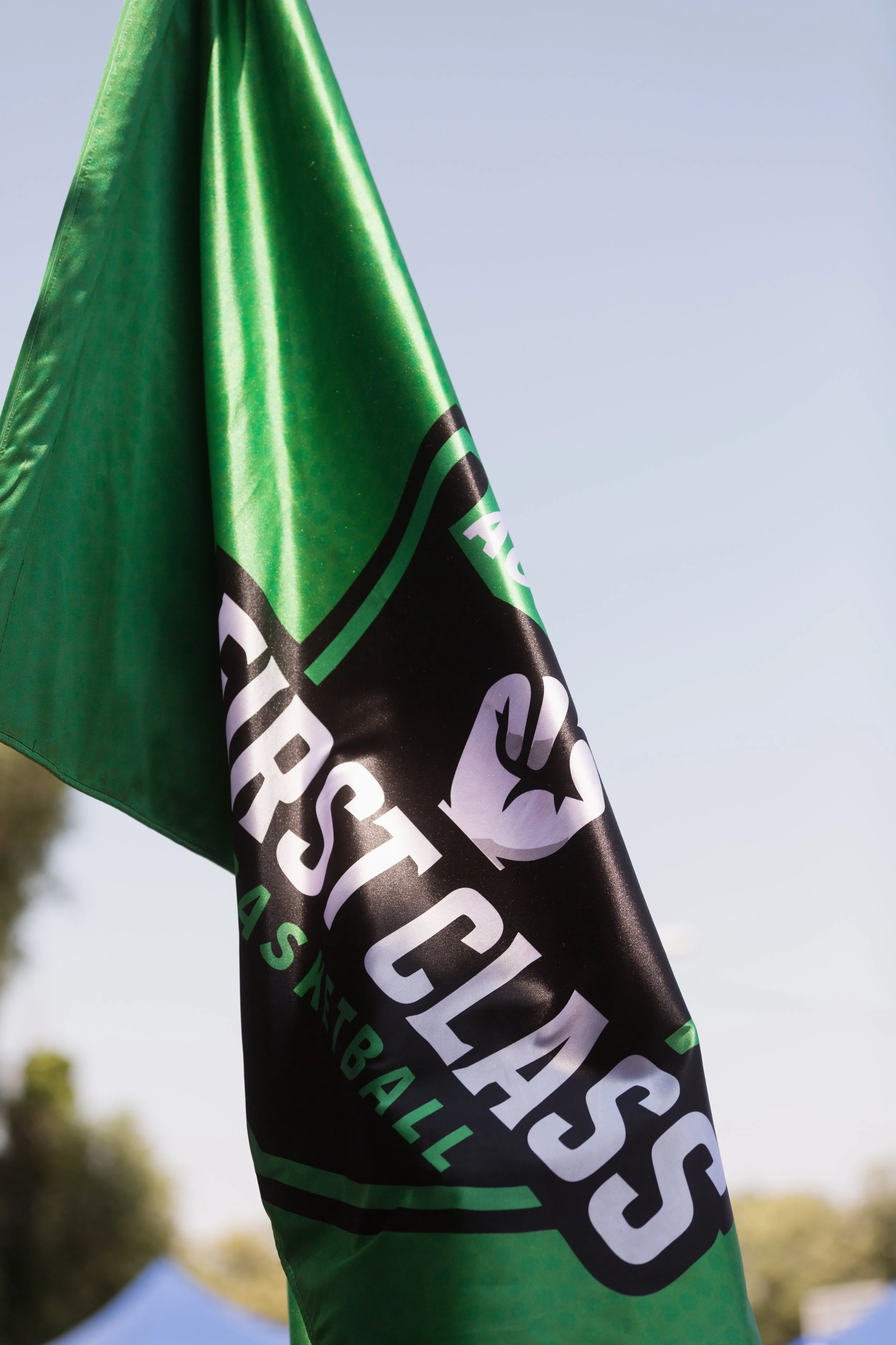 Close-up of a green and black banner or flag with white text, outdoors with a blurred background.