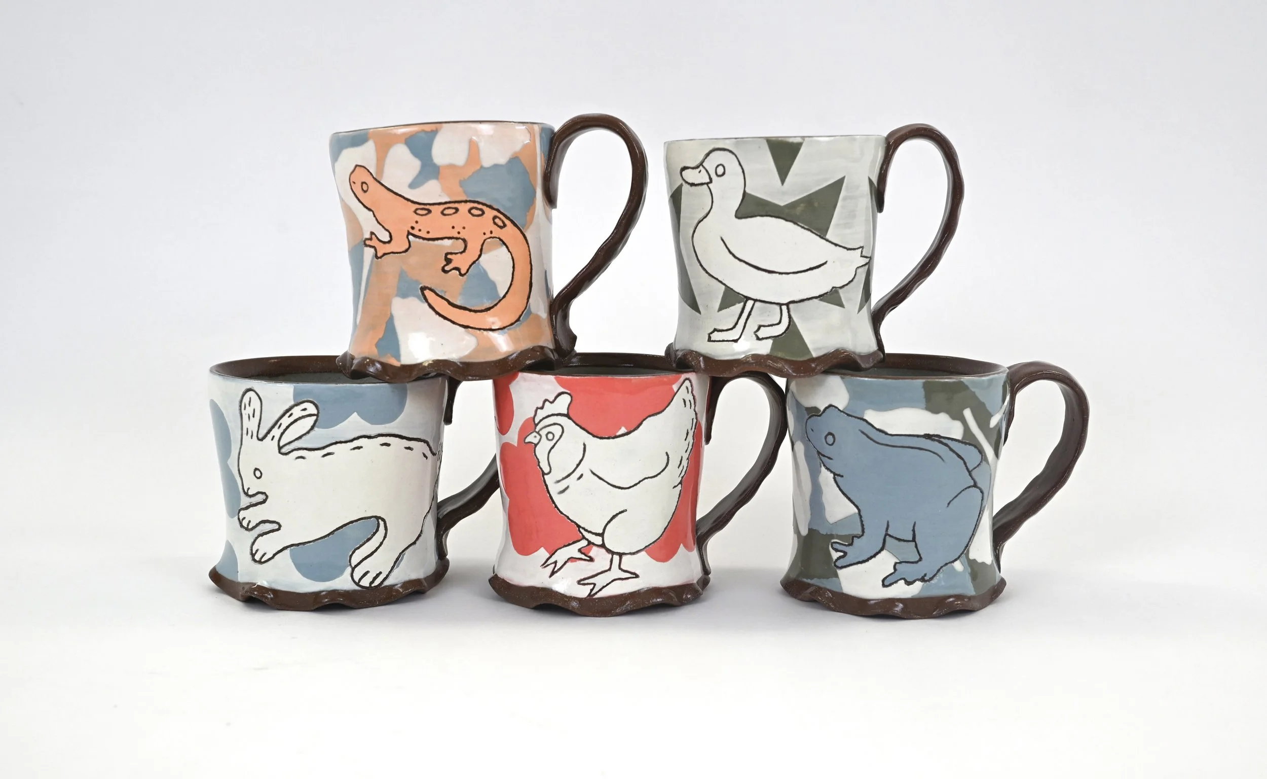Six ceramic mugs with animal illustrations and abstract backgrounds, stacked in two tiers against a plain white surface.