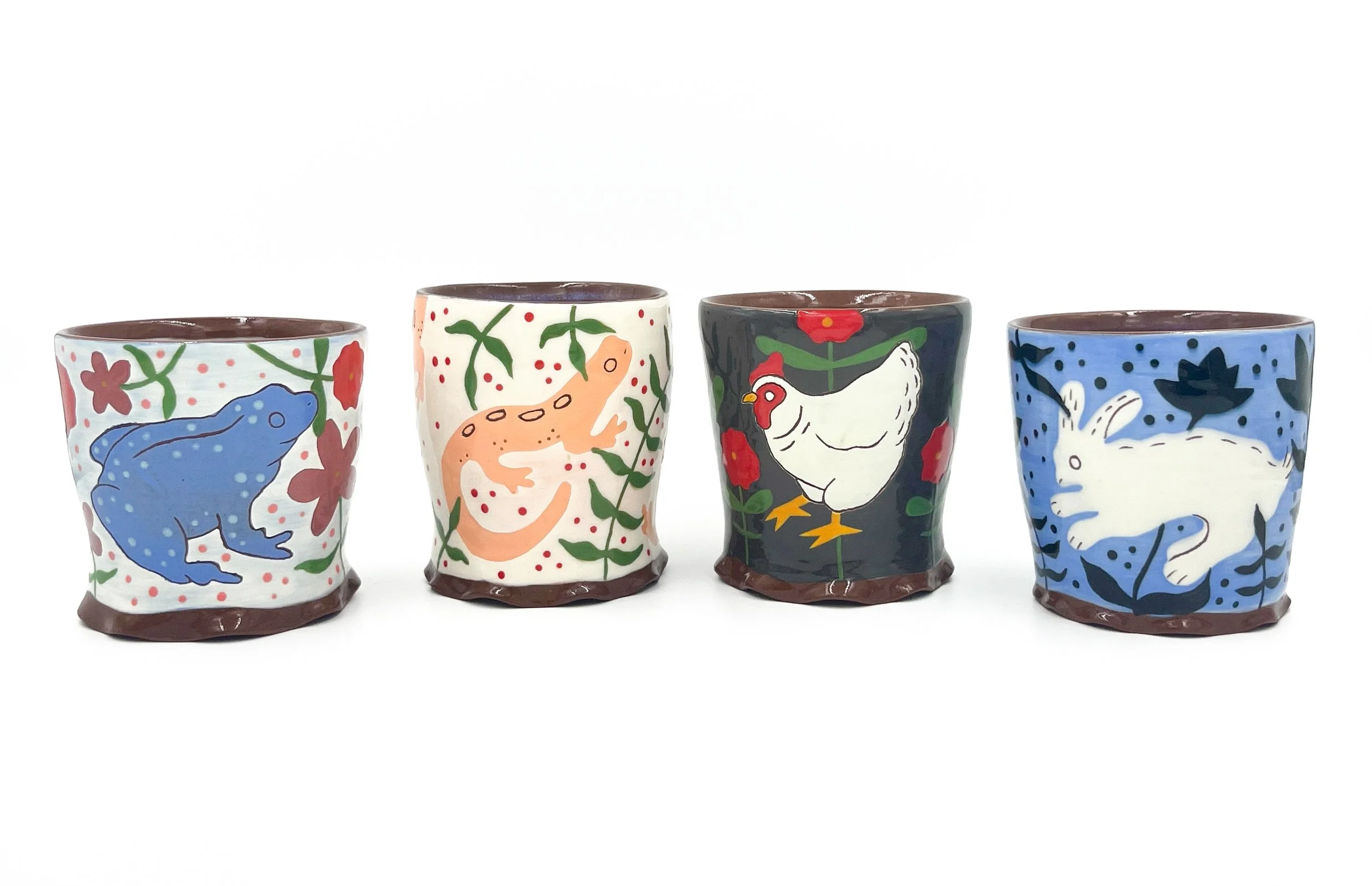 Four colorful ceramic plant pots with animal and nature designs, placed in a row against a white background.