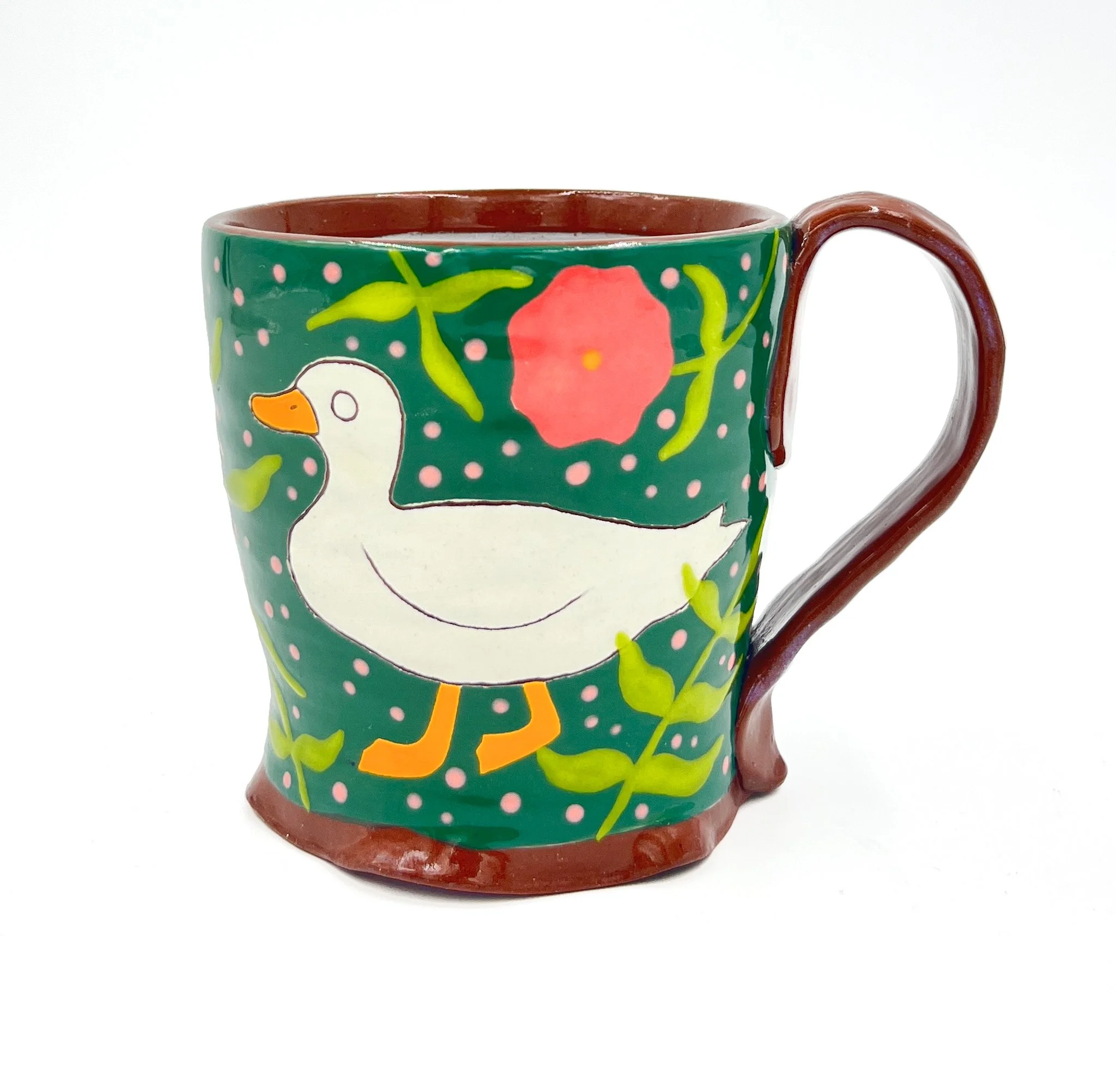 Ceramic mug decorated with colorful, whimsical holiday-themed illustrations, including a snowman, a red ornament, and green foliage on a green background.