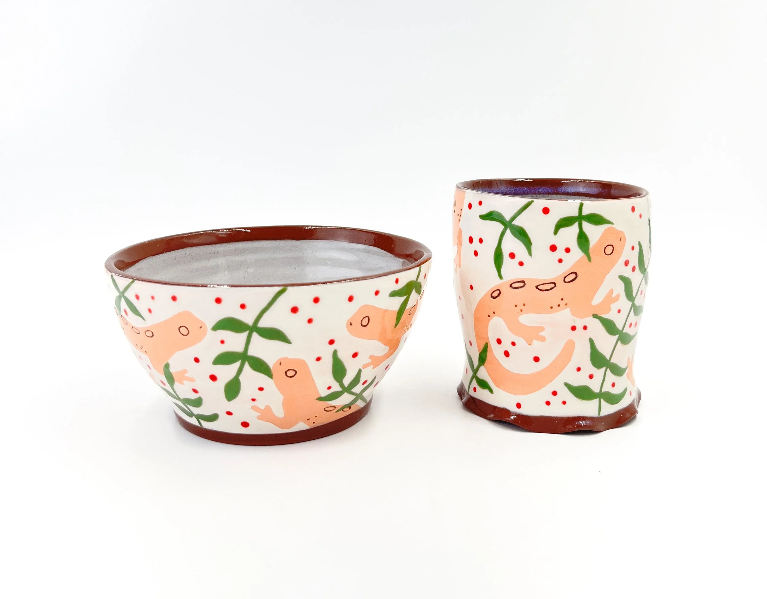Two painted ceramic pots with colorful dinosaur and plant designs on a white background.