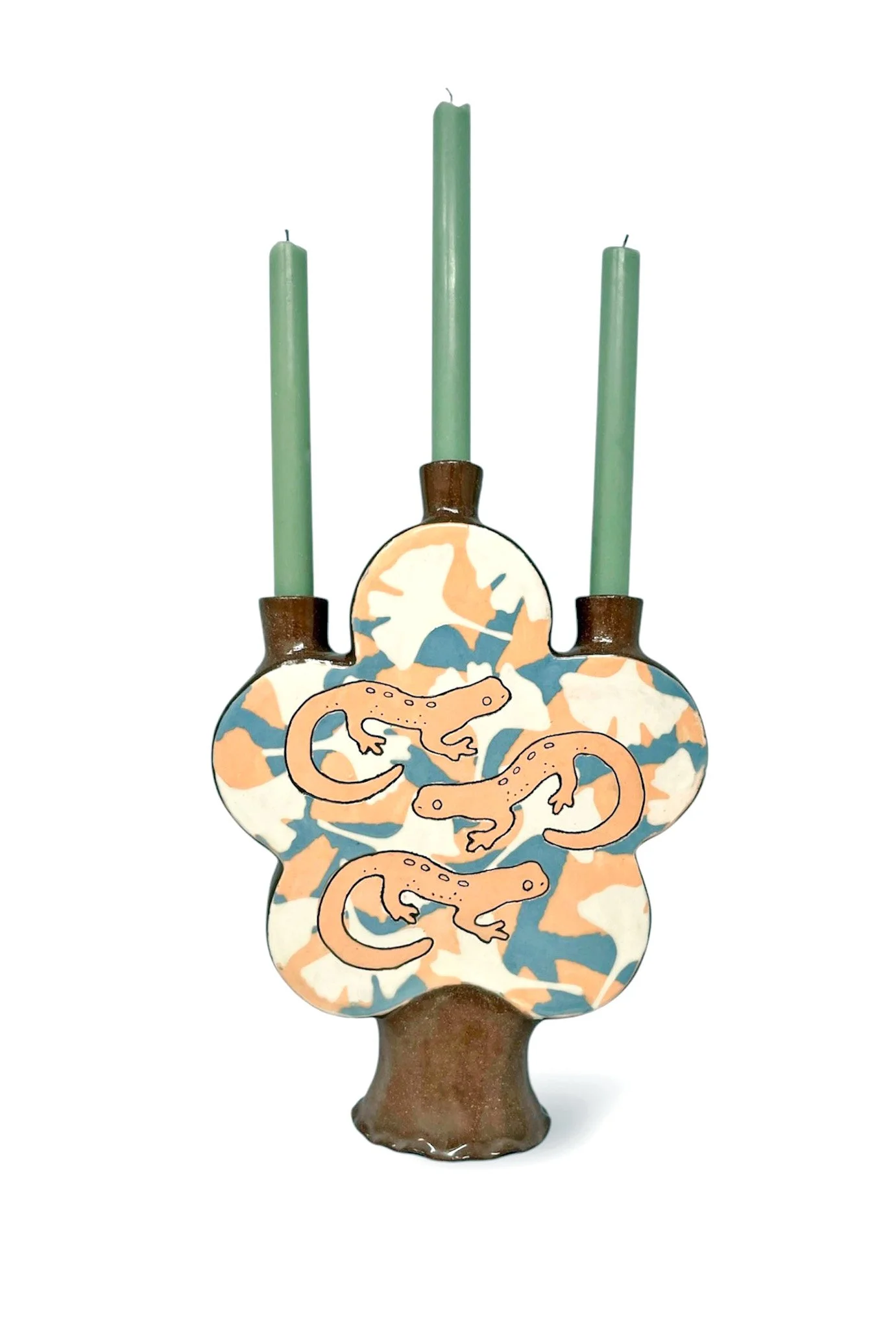 Ceramic decorative piece resembling a leopard-print vase with painted lizards on it, topped with three green candles.