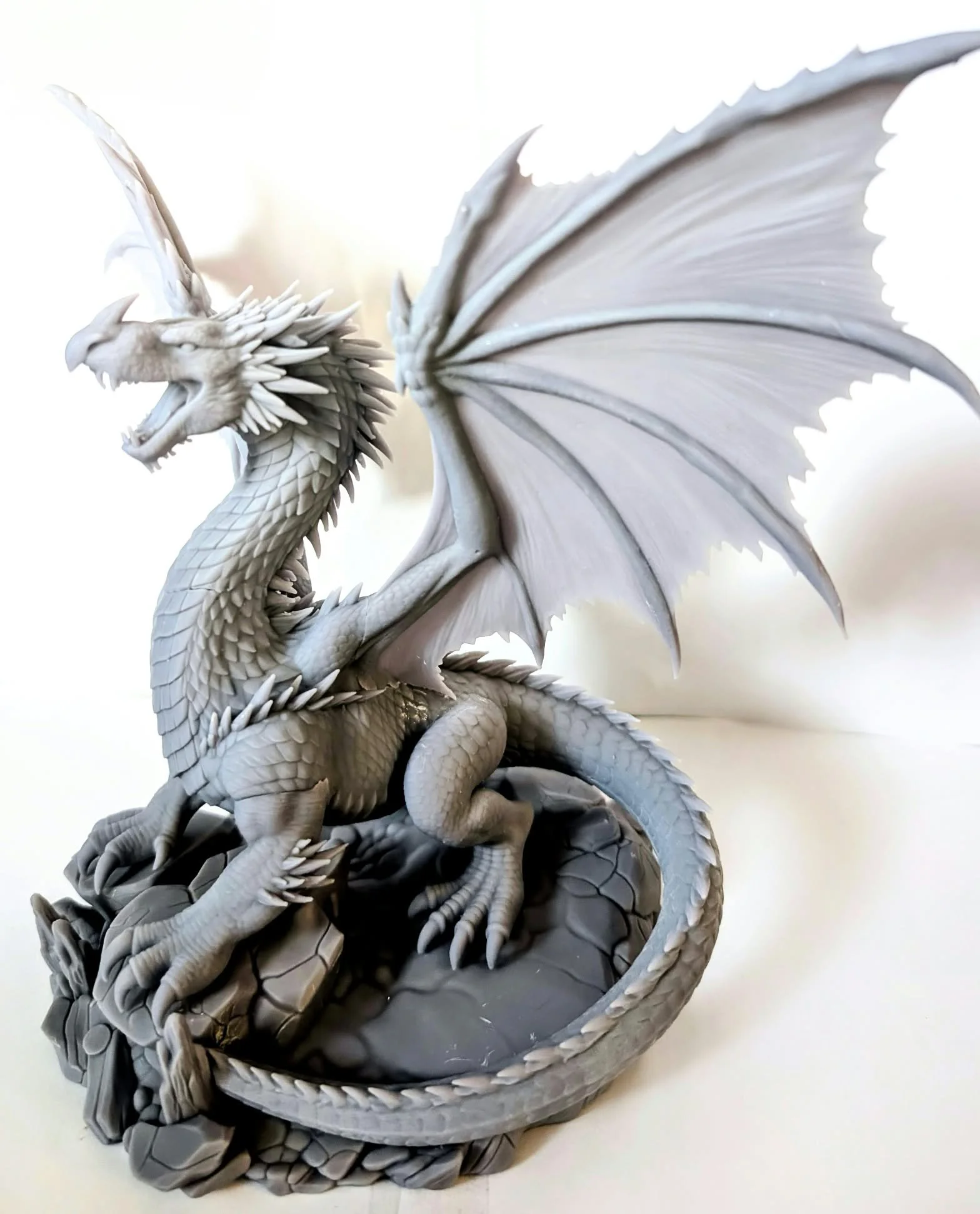 Adult Red Dragon resin miniature, unpainted, three-quarter view: wings raised, jaws open, tail coiled around its rocky base