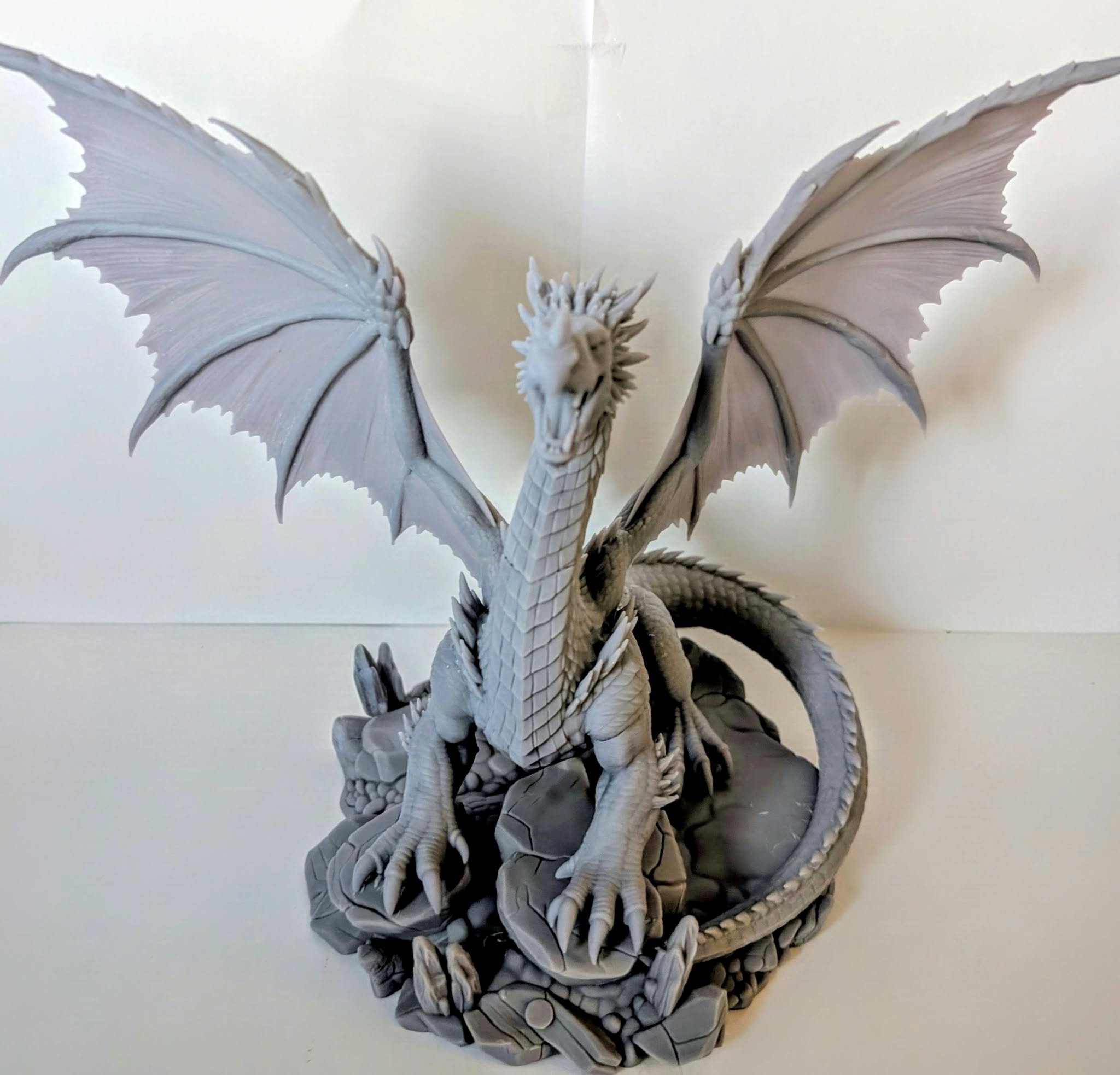 Adult Red Dragon resin miniature, unpainted, front view with wings spread wide over its rocky base