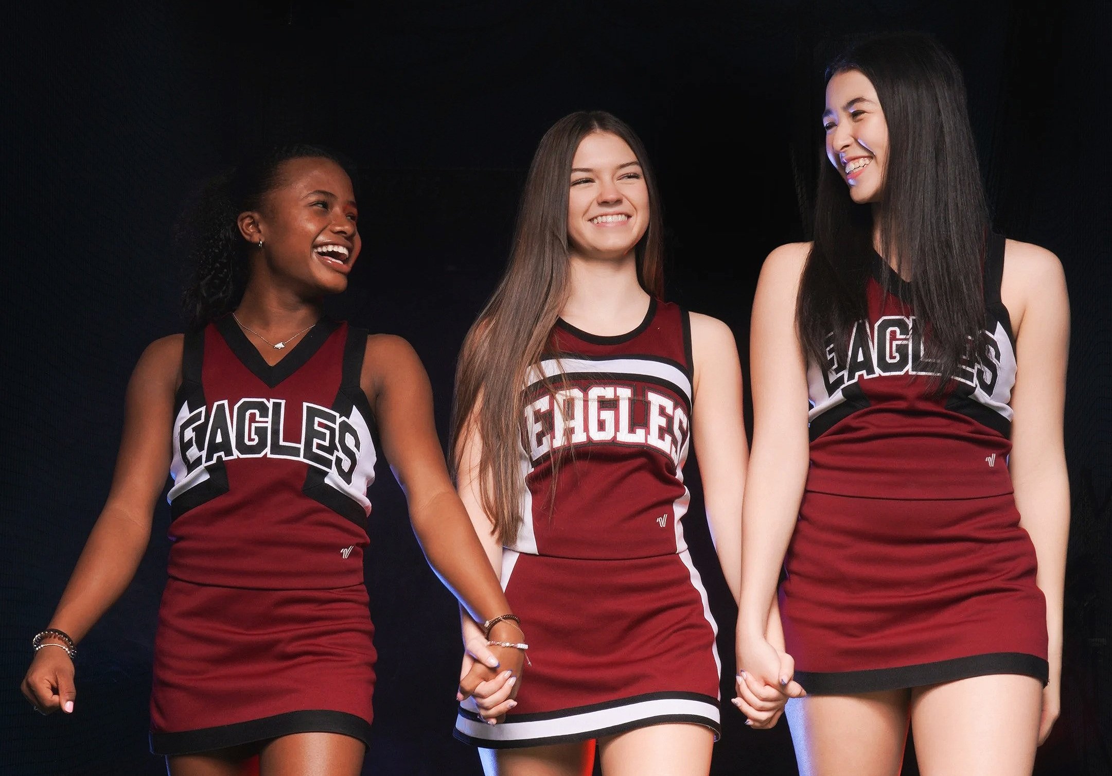 Three cheer athletes during a professional team media day photo session in South Florida