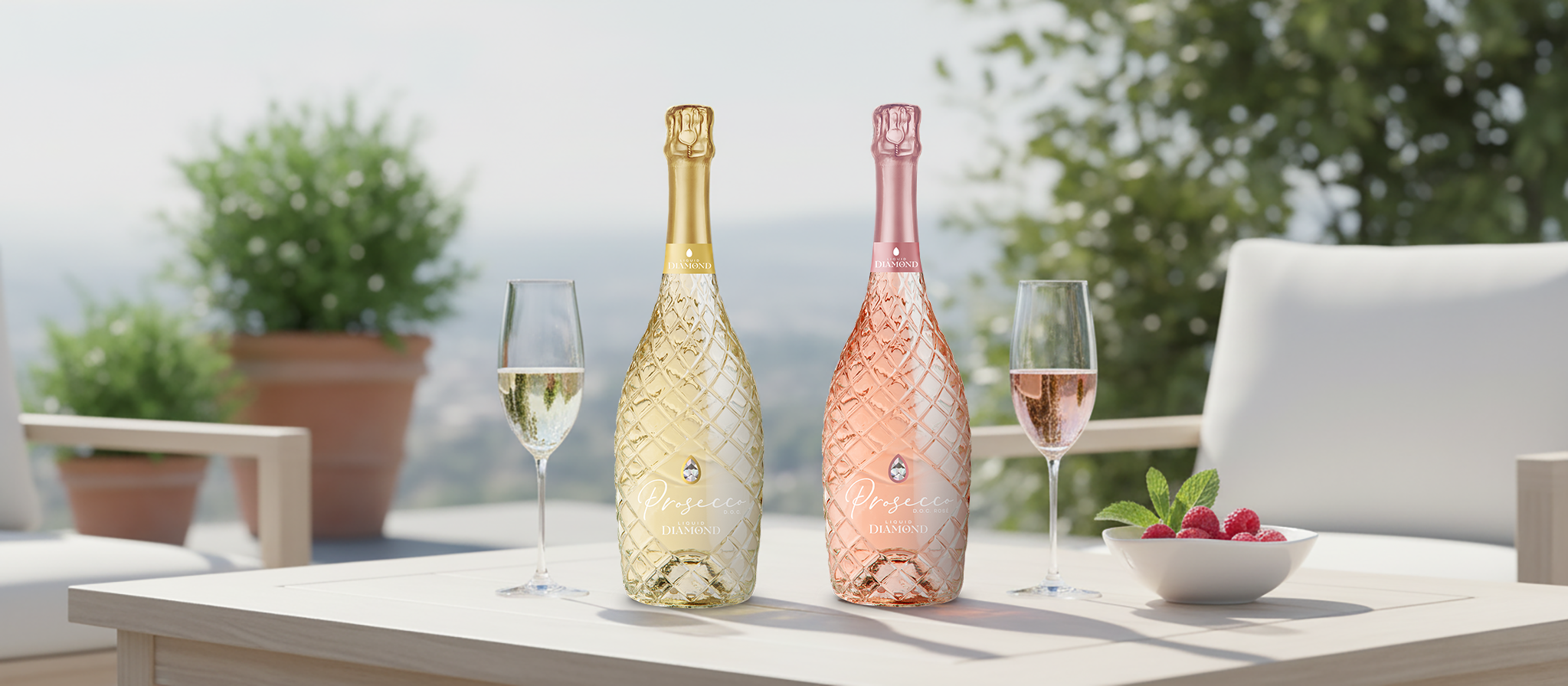 Two bottles of sparkling wine, one gold and one pink, on a table with two glasses of champagne, outdoors with potted plants and a scenic view in the background.