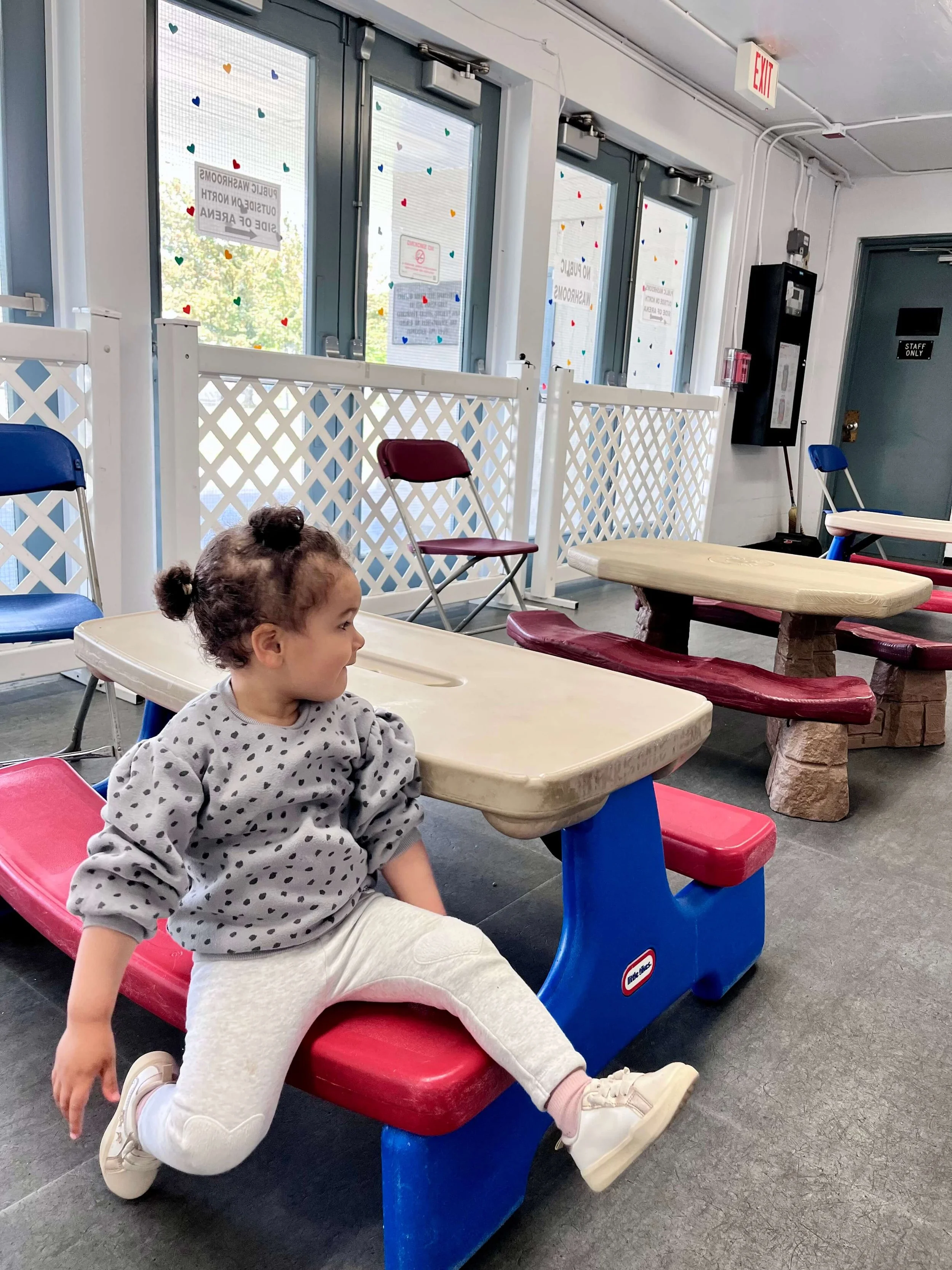 Little girl sitting on a plastic picnic table and chair in the Kerrisdale Play Palace.