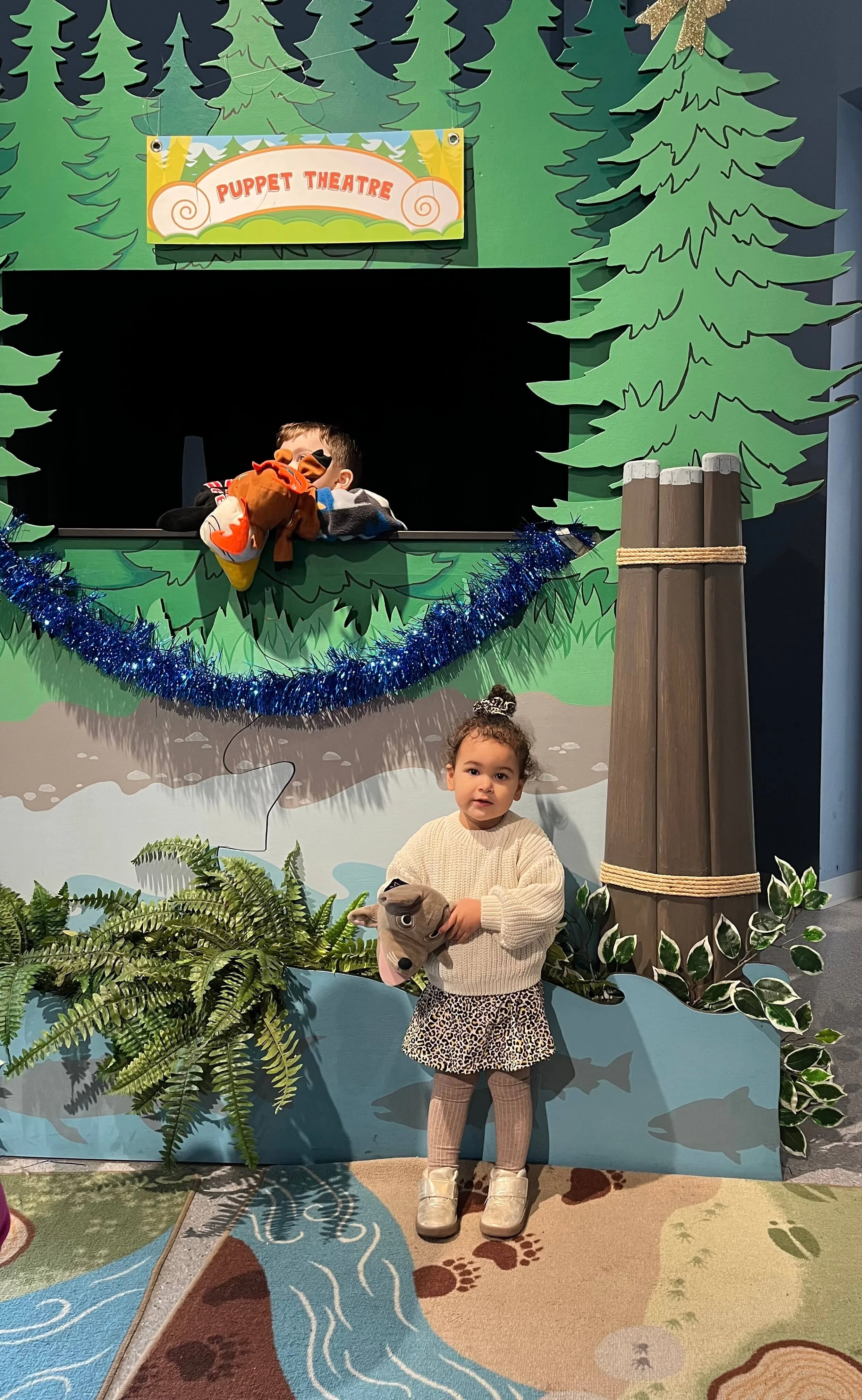 Little girl standing in front of a puppet show.