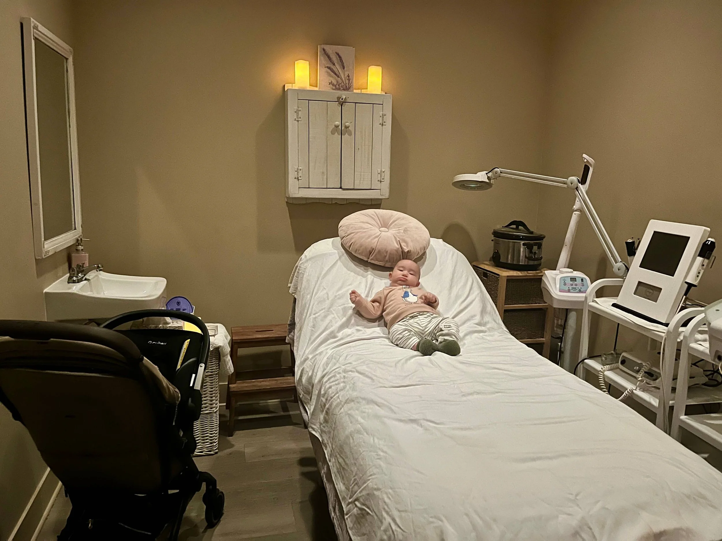 Baby lying on a spa bed with a stroller in the room at Le Petit Spa