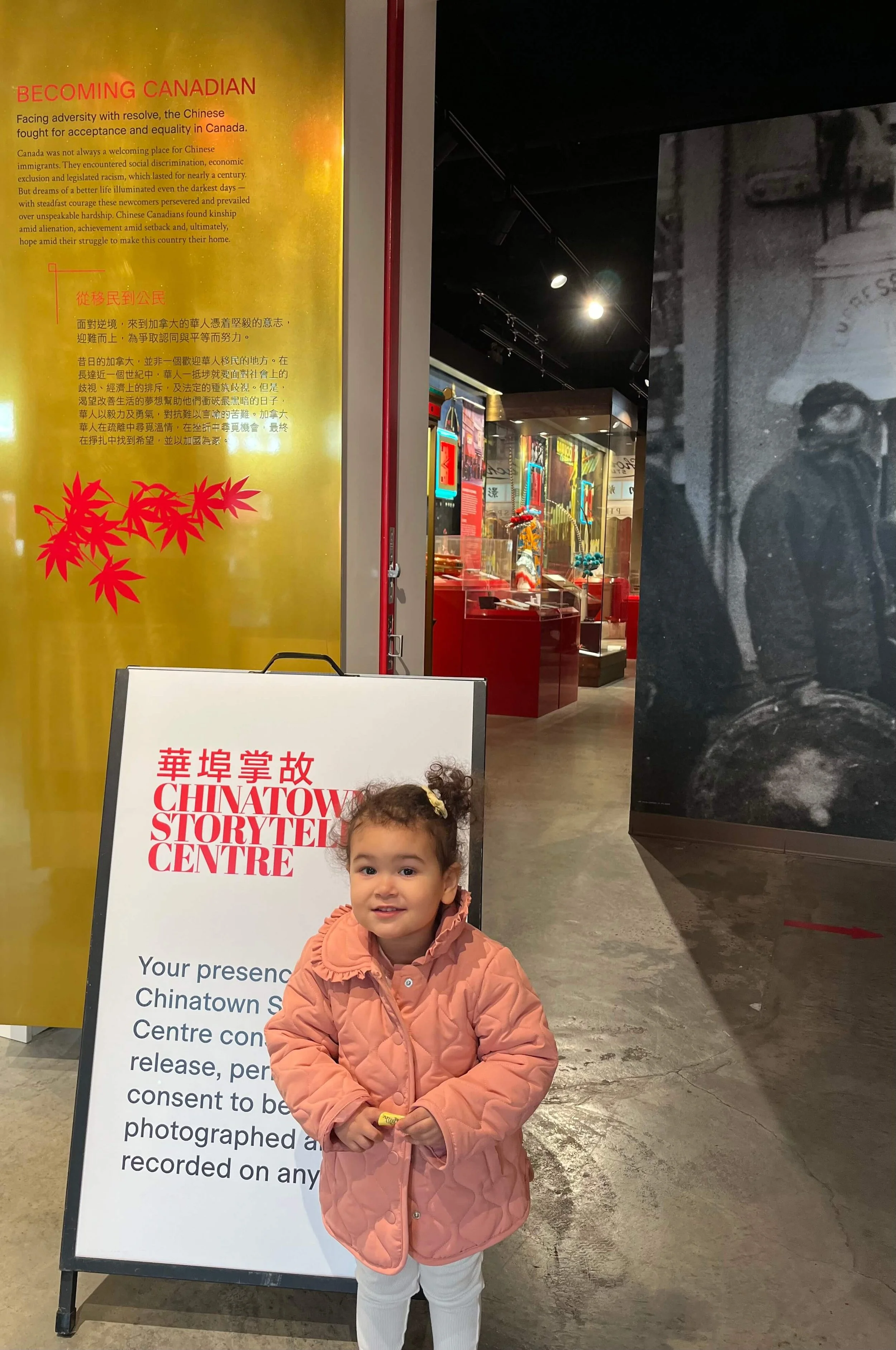 Little girl in pink coat standing in front of the Chinatown Story Centre entrance