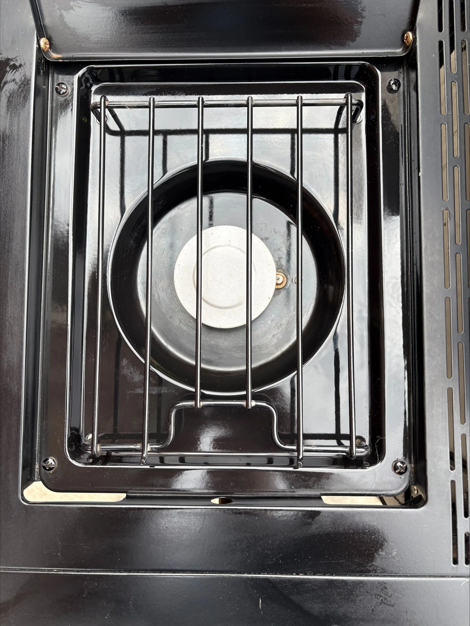 Top view of a small stovetop with a single burner and metal grill.