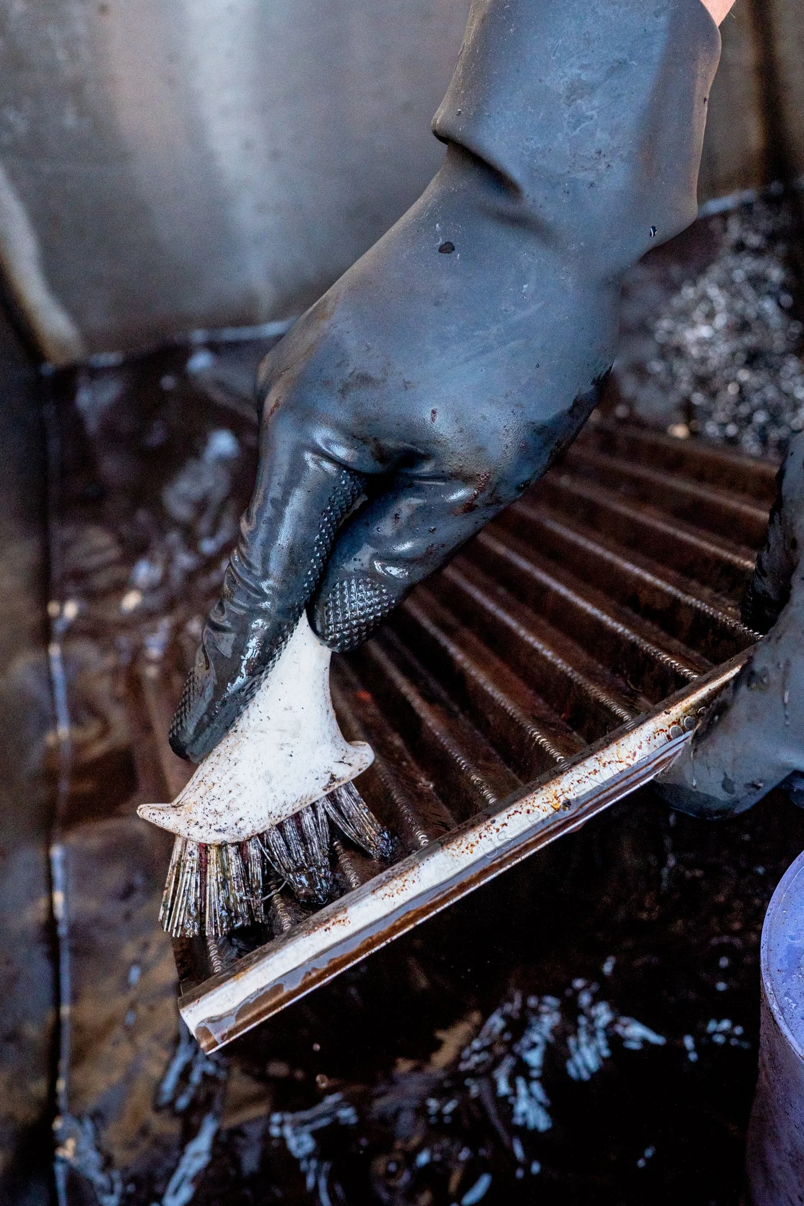 Grill brush removing built-up carbon from outdoor kitchen grill in Oklahoma City
