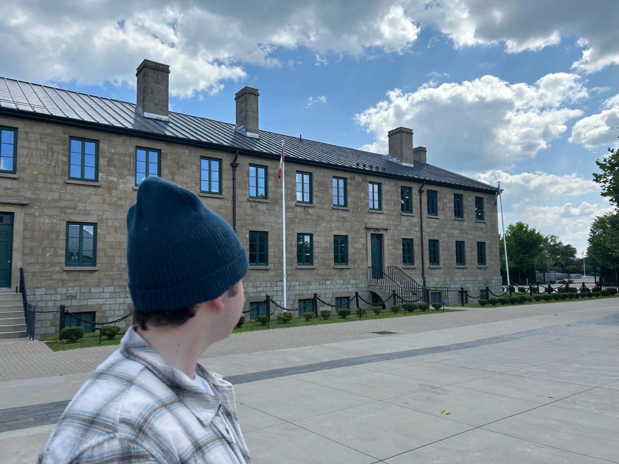 Person wearing a navy knit beanie looking toward a historic stone building